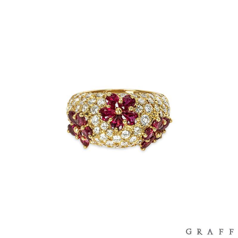 An 18k yellow gold diamond and ruby ring by Graff. The ring is composed of pave set round brilliant cut diamonds with 3 flower motifs made up of 5 individual rubies as petals. The rubies have an approximate total weight of 1.50cts and the round