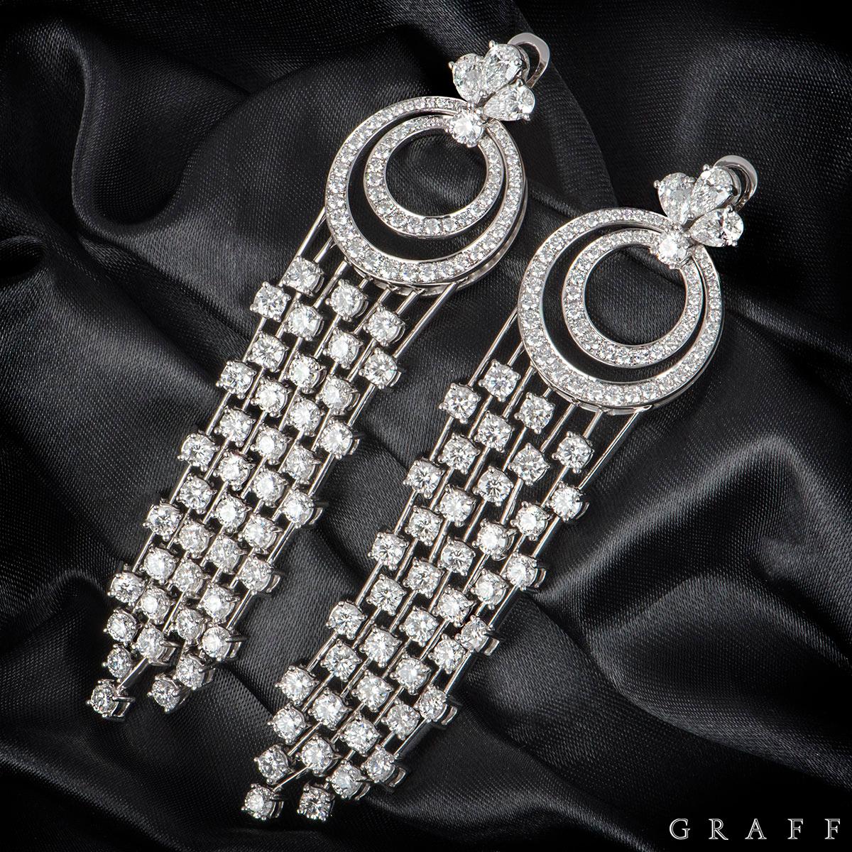 A striking pair of 18k white gold diamond set drop earrings by Graff. The earrings are each composed of 3 pear shaped diamonds at the top with two circular openwork motifs, one inside the other set with pave round brilliant cut diamonds and