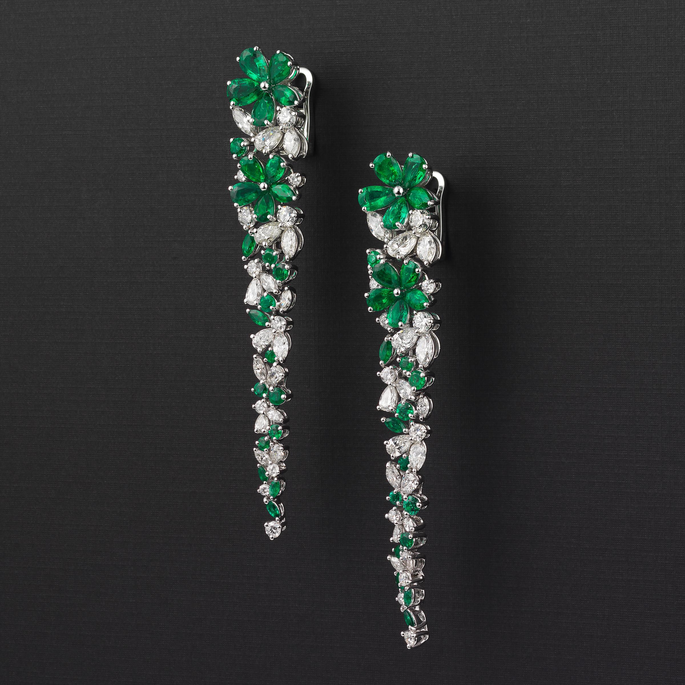 Exceptional Graff dangle earrings of floral inspiration radiating red-carpet glamour and exquisite elegance and showcasing approximately 9 carats of glittering fine white diamonds and 12 carats of vivid green emeralds, all flawlessly set in 18 karat