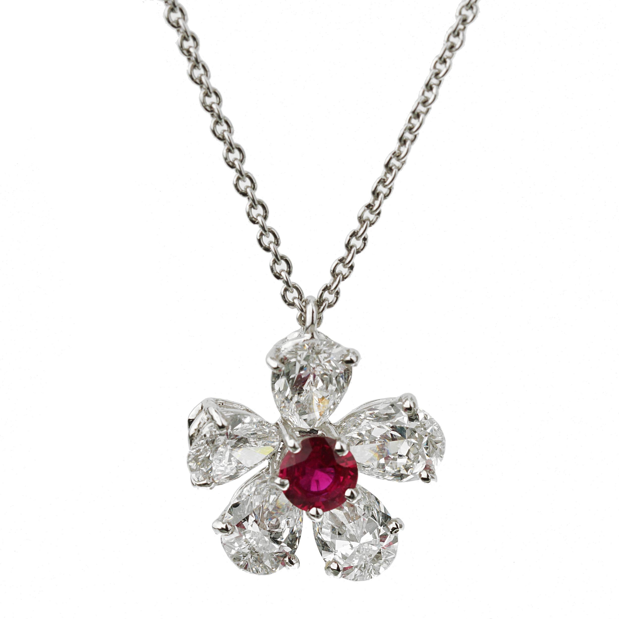 An iconic authentic Graff pendant necklace showcasing 5 pear shaped diamonds surrounding a ruby in a floral motif. The pendant and necklace are platinum, with a total length of 17