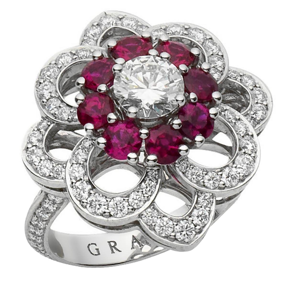 A magnificent Graff diamond cocktail ring showcasing a brilliant-cut diamond and ruby frame ppenwork floral frame. The ring has round brilliant cut diamonds running down both sides of the band mounted in platinum. Signed Graff, with a ring size of 4