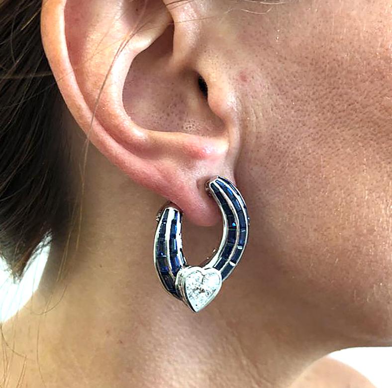 GRAFF Sapphire Diamond Heart Hoop Earrings in 18k White Gold.

A contemporary pair of torqued hoop earrings by Graff intended to rest asymmetrically on the ear. Ribbed channels of calibré-cut sapphires cascade down the ear into charming hearts of