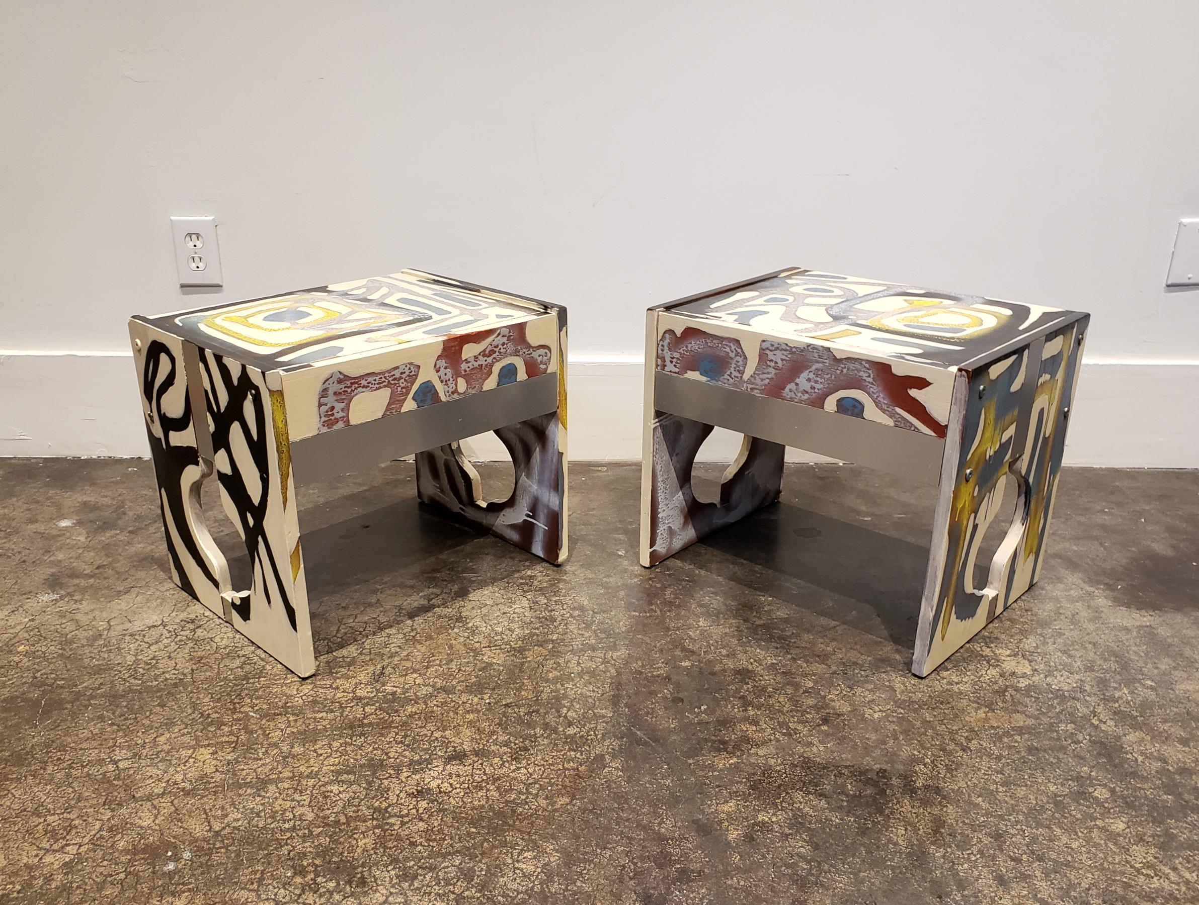 All-over abstract composition hand painted in acrylic and spray-paint by artist Lionel Lamy on a pair of 1970s teak wood, low nightstands. Nightstands have decorative cut-outs, metal veneer elements and one pullout drawer each. Meant to be paired