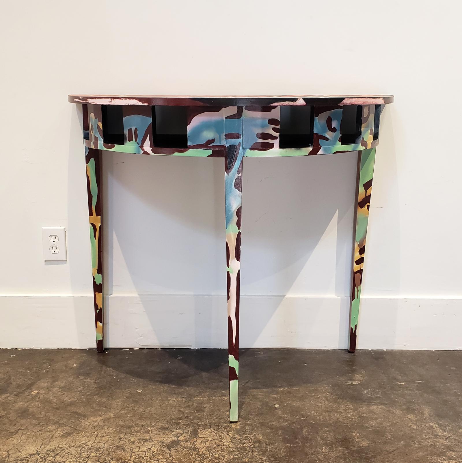 All-over abstract composition hand painted in acrylic and spray-paint by artist Lionel Lamy on a prototype Jacques Lamy-designed console table. Demilune shape with open cubby holes under table top for storage, all raised on three tapered legs.