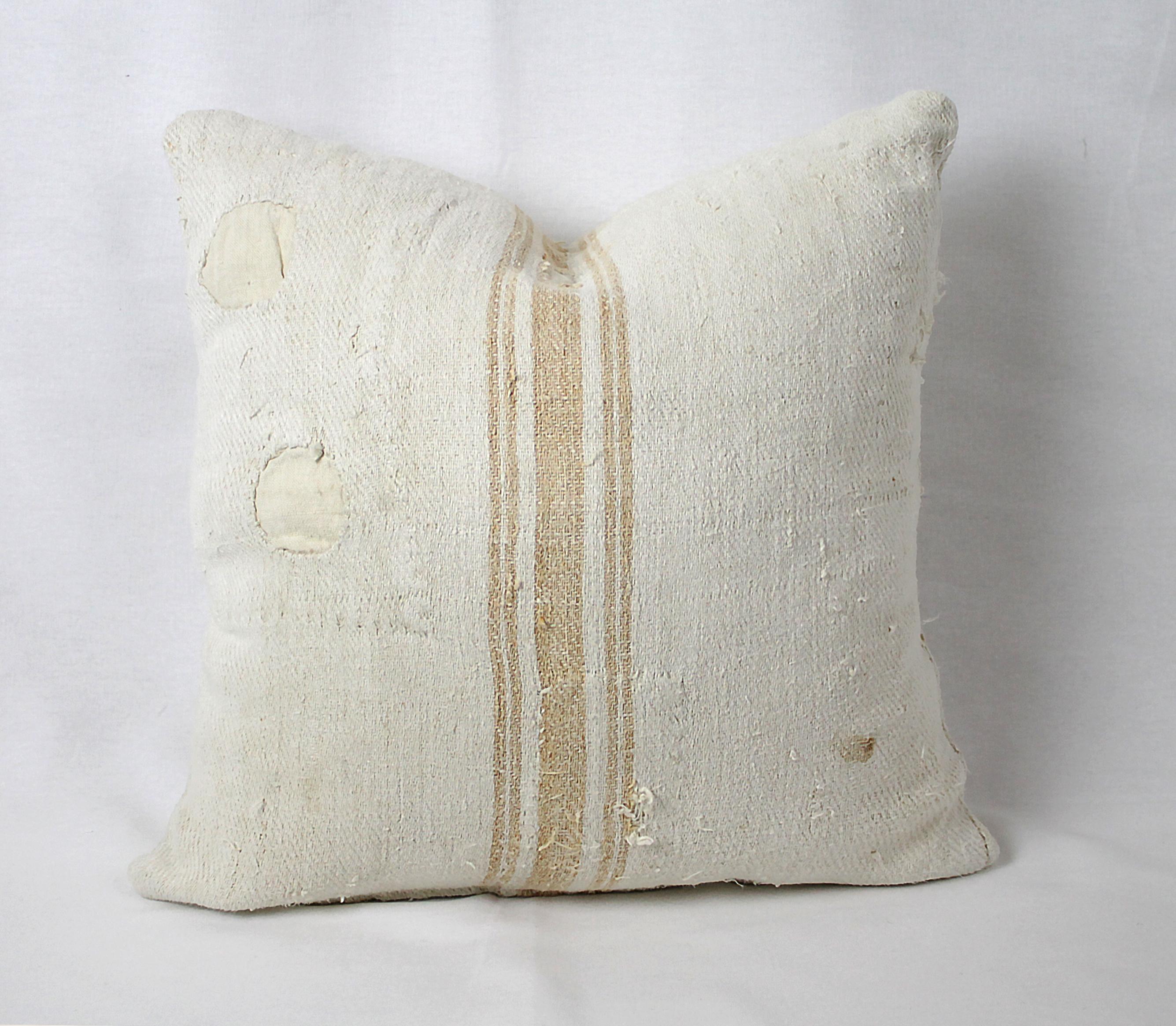 We make these pillows from old grain sacks from Eastern Europe. The pillow has a light orange triple stripe down the center, and the body is a medium oatmeal color. They are sewn with a zipper closure, and since we prewash all our vintage fabrics in