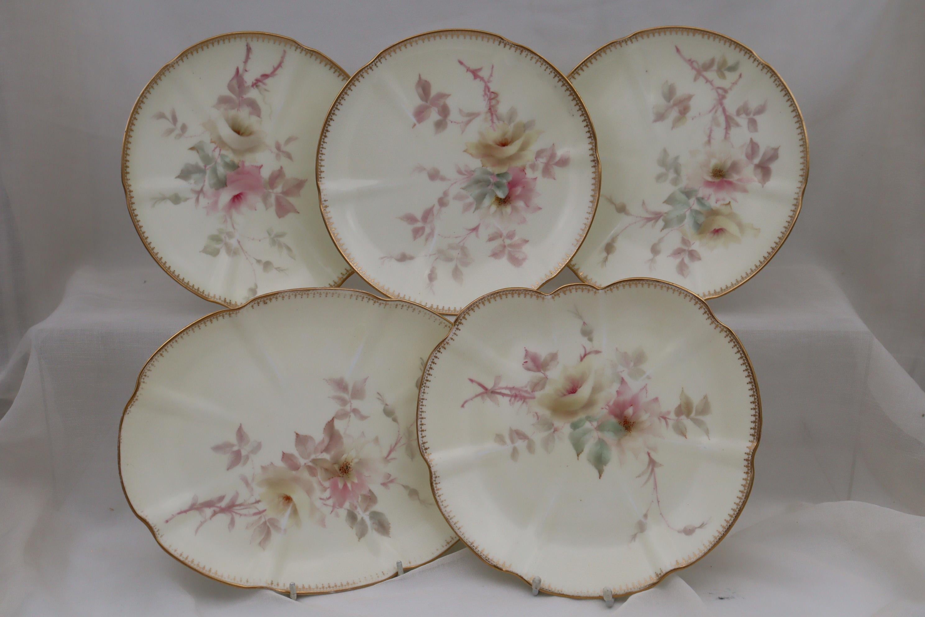 This hand painted and gilded porcelain part dessert service comprises two low comports and six plates and was made by the firm of Grainger's of Worcester. The very pretty painting of roses in delicate pastel colours on a pale cream ground is