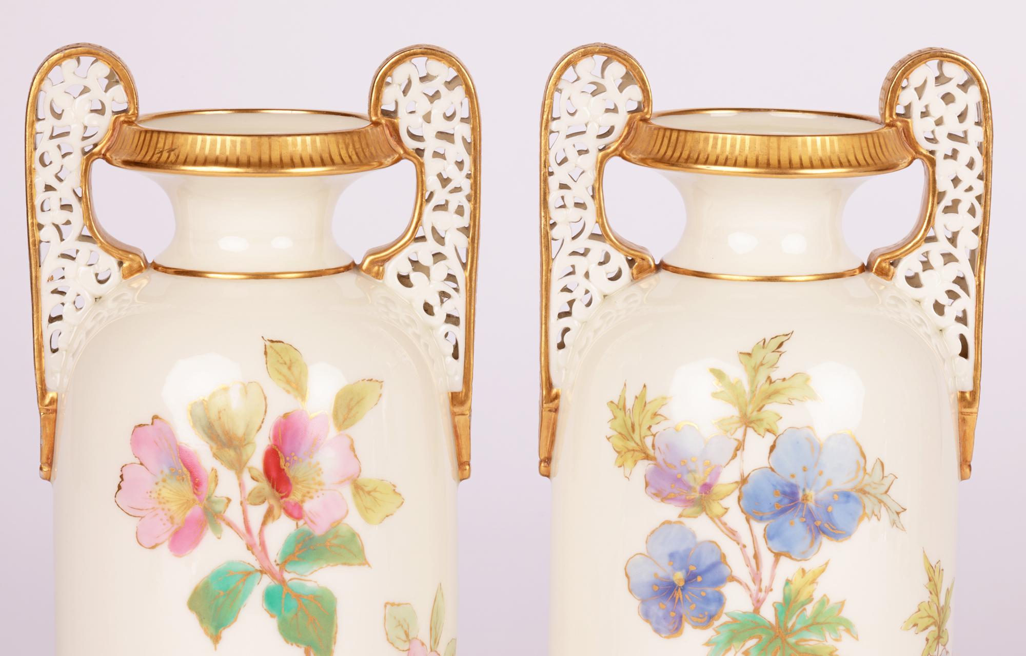 A very fine pair English twin handled porcelain vases painted with flowers by renowned makers Grainger Worcester and dating from the 19th century. The vases of tall cylindrical shape stand on a narrow round unglazed foot with slightly recessed base