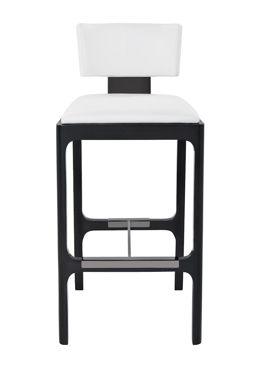 Bar stool with tight upholstered seat and back. Sleek rounded show-wood frame with metal lumbar stem and foot support detail.
   
Shown upholstered in Powell & Bonnell Cattle Call, Bright white leather with Americano ash frame and polished black