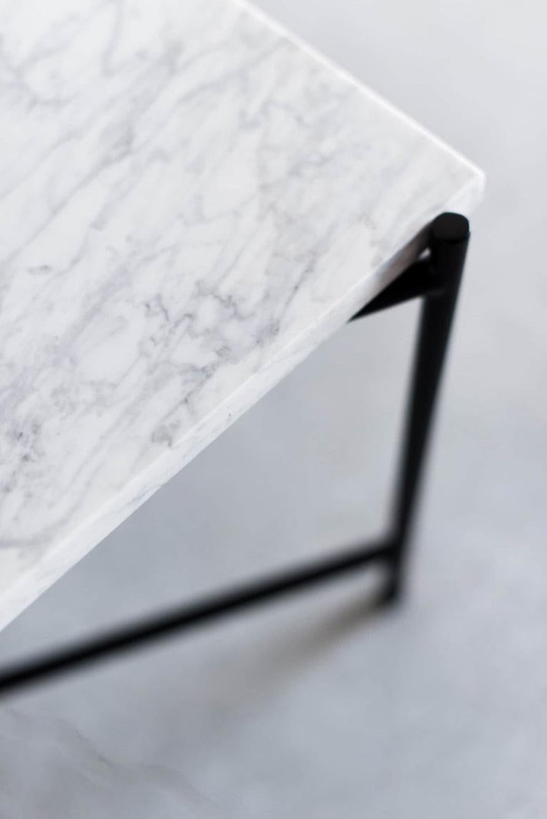 The Granada Coffee Table emphasizes a sophisticated balance between minimalism and contrast. The Carrara marble top features beautiful, natural veining that is complemented by the matte black base. The X-shaped runner between the four legs provides