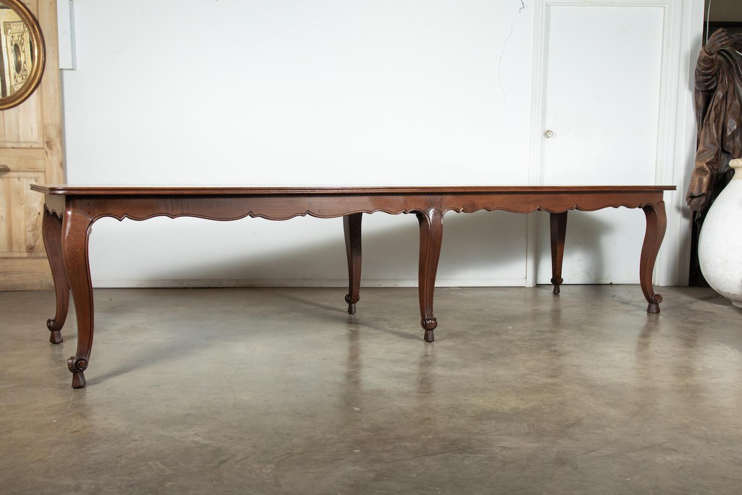 A grand French Louis XV style oak chateau dining table having a framed parquet top with a scalloped apron raised on six graceful cabriole legs ending in scrolled French toes on pegs. This Classic country French dining table retains its beautiful