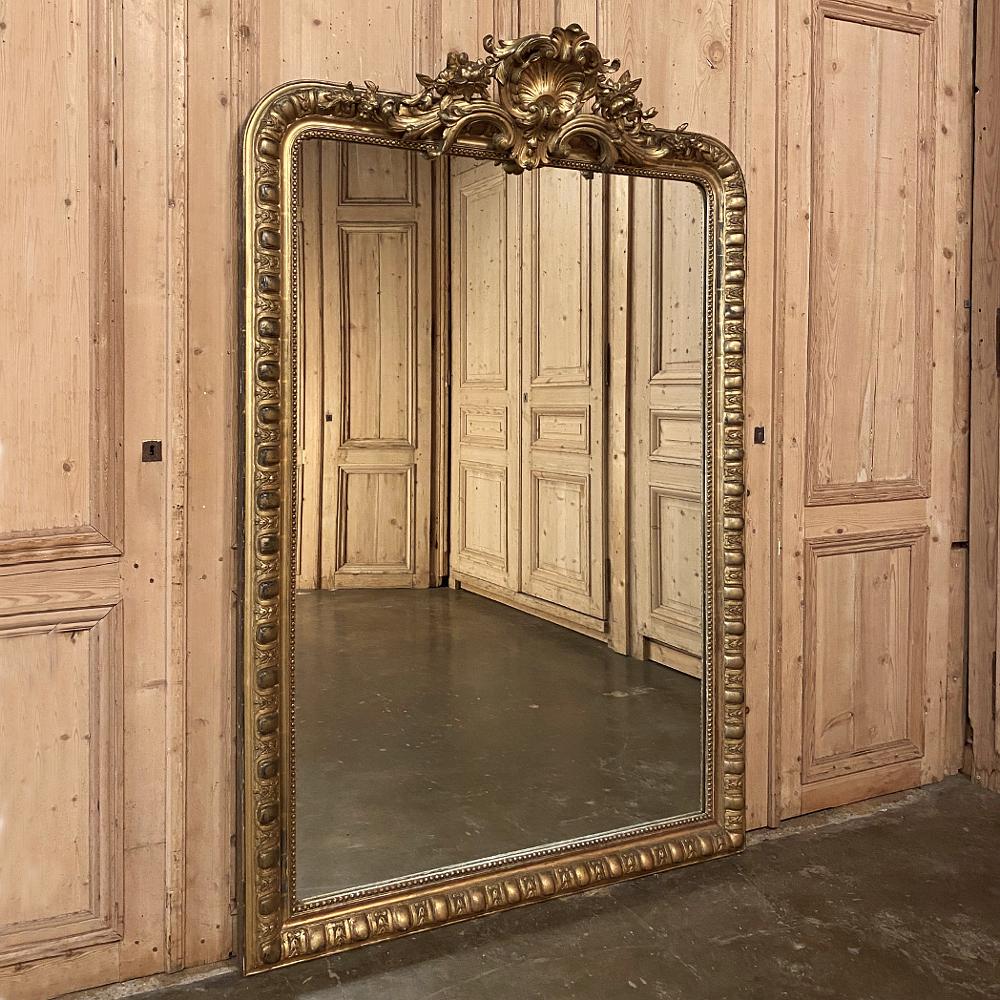 Grand 19th century French Louis XIV gilded mirror was handcrafted during the Napoleon III period and stands over six feet tall, and will command an instant presence in any room! Boasting its original water gilding, it features a stunning shell,