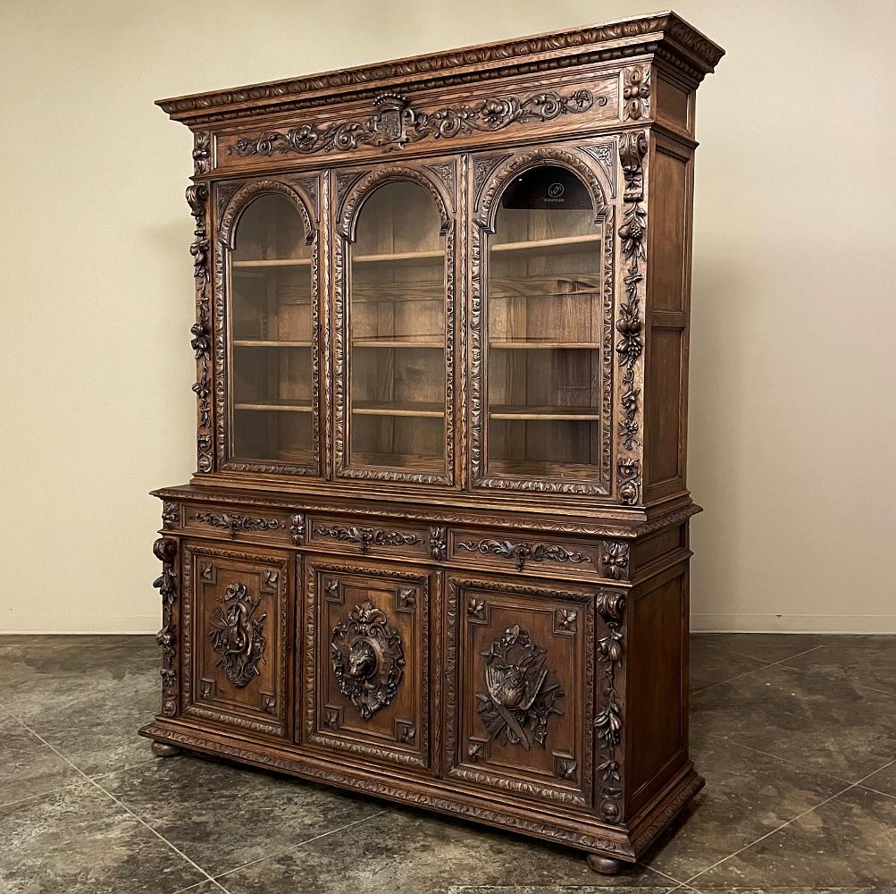 Grand 19th century French Renaissance revival triple hunt bookcase is a work of the cabinetmaker's and sculptor's art on a large scale, perfect for a larger room! Designed with triple arched glazing above, and lavish relief carvings on three doors