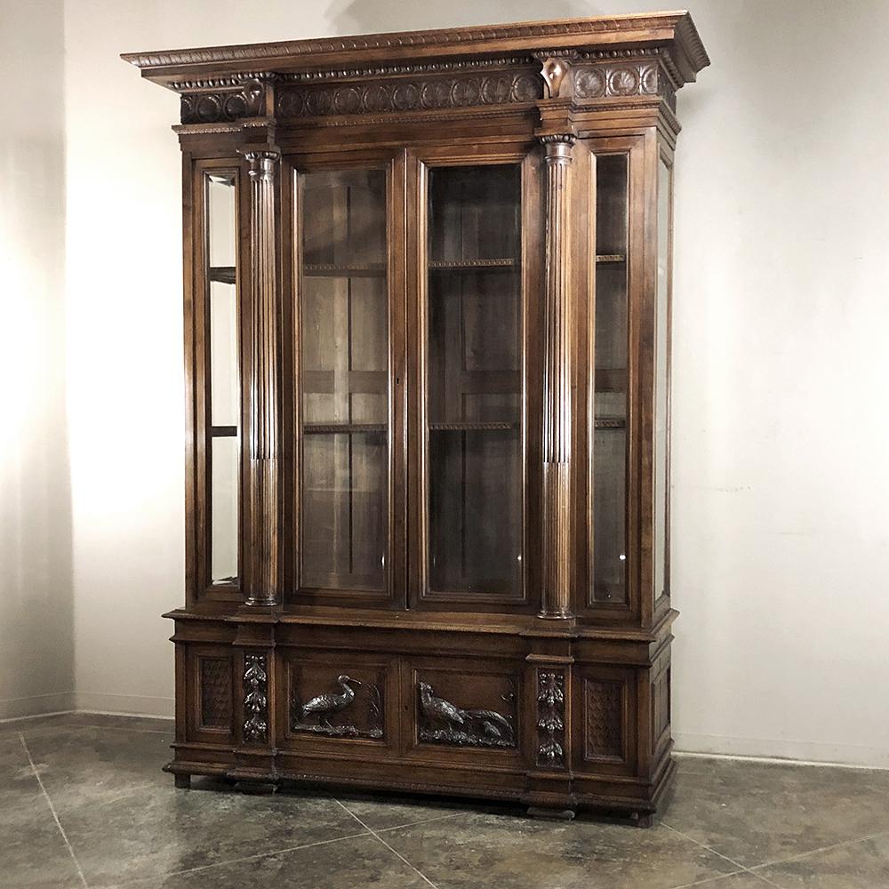 Grand 19th Century Italian Walnut Neoclassical Bookcase is a study in the artistic sculpture of Northern Italy.  Sculpted in solid, sumptuous walnut, it features wildlife scenes which appear at the bottom door panels in glorious full relief