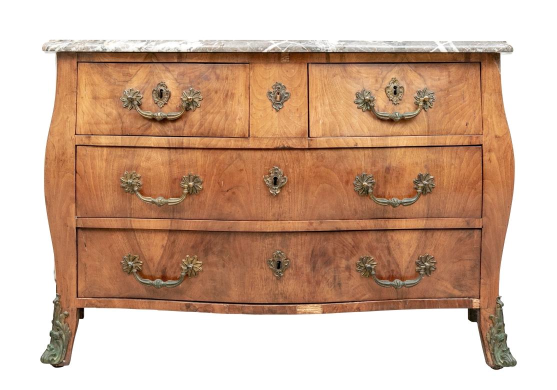 A Classic French Bombé Two-Over-Two Chest in handsome Cherry Finish and having large Dramatic Drawer Pulls, Key Escutcheons and leg mounts. The Chest is topped with a fine and well grained Marble Top in Striated Brown and White with a lovely shaped