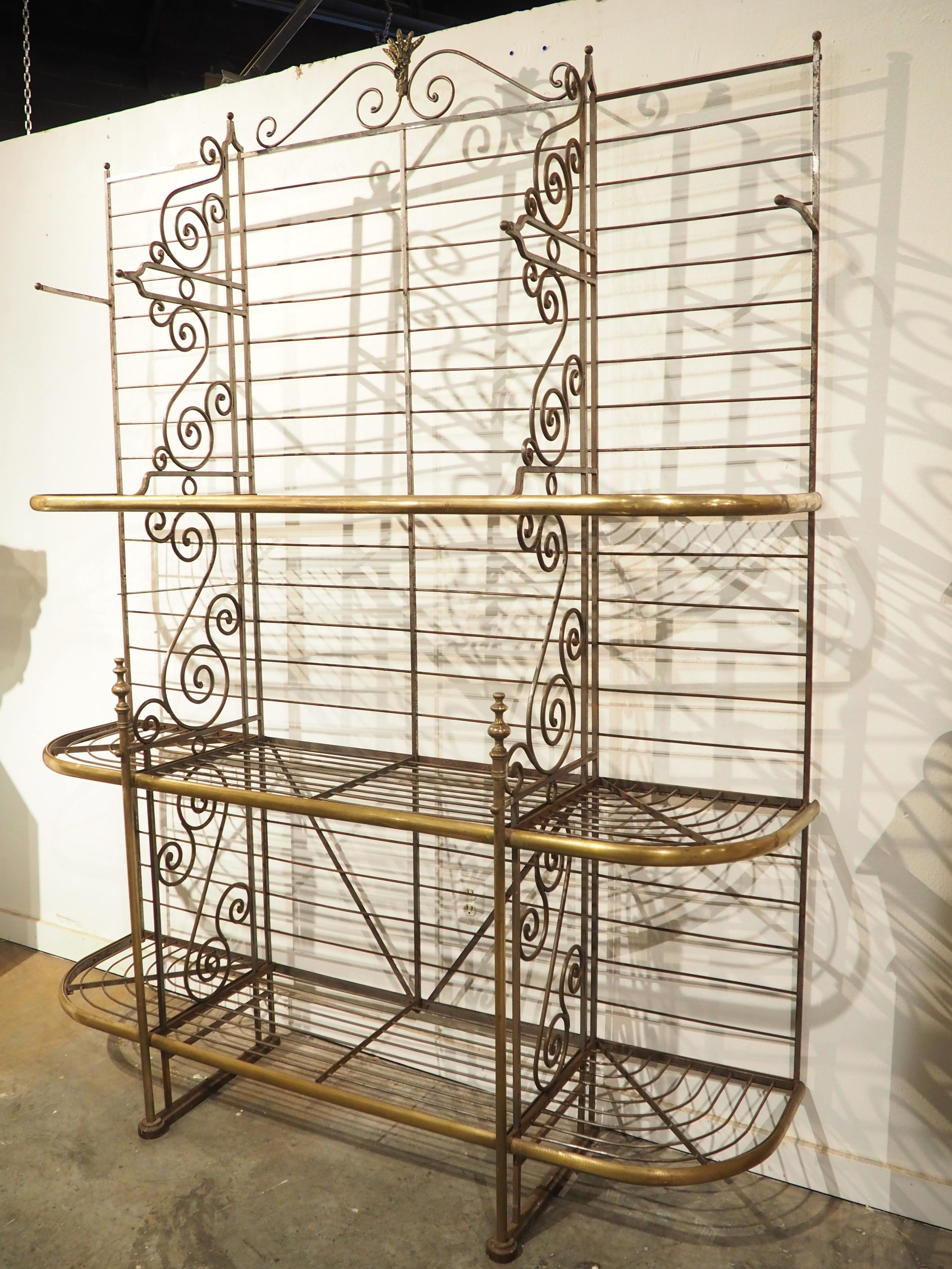 More information coming soon…

This grand baker’s rack is comprised of a slatted iron frame with brass embellishments, such as the bundled wheat motif of the scrolled crest and the edges of each of the three shelves.  The shelves are divided by