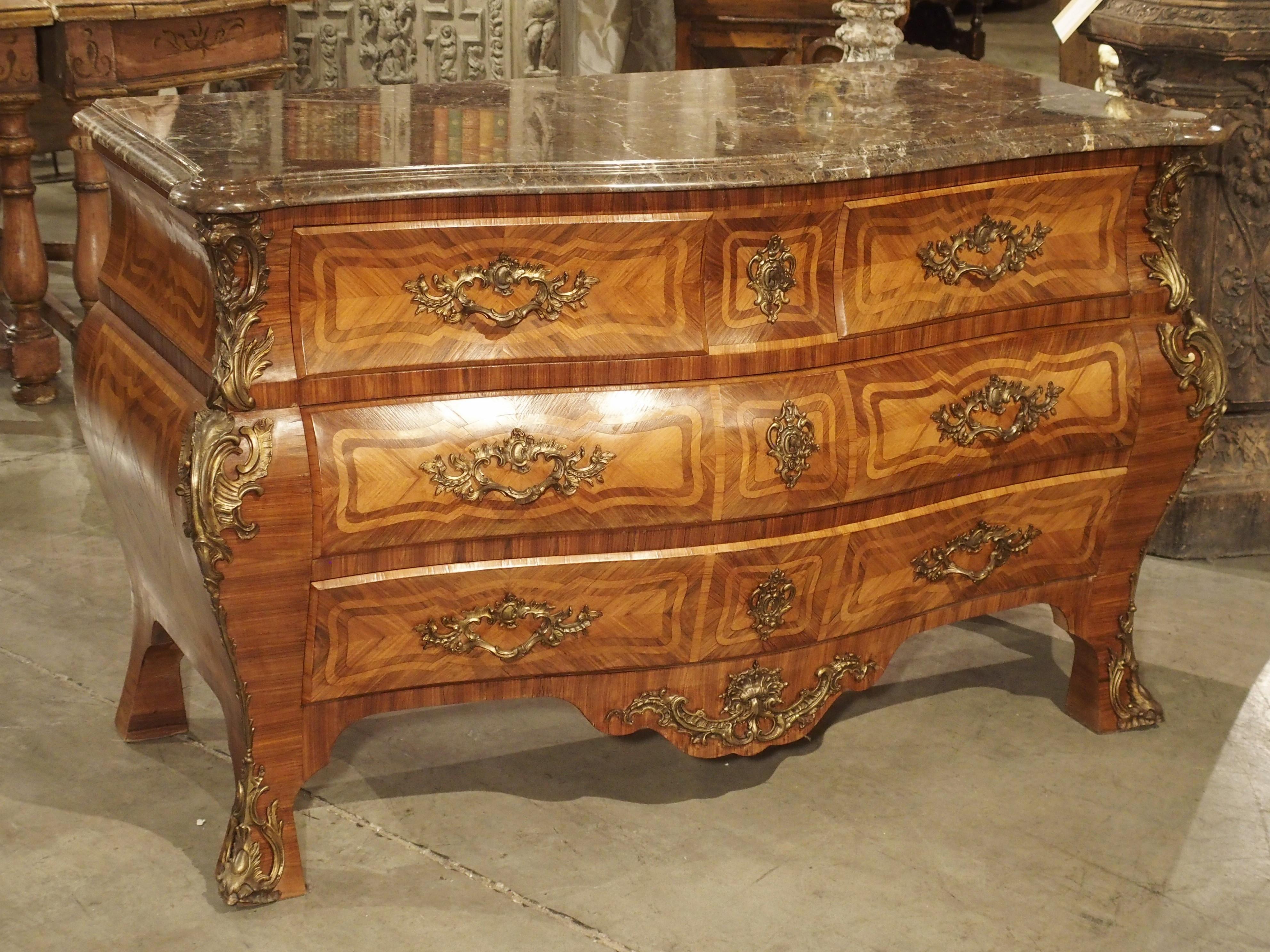 This grande French commode with beautiful veneered panels and numerous bronze ormolu mounts dates to the beginning of the 20th century. The commode is in the Louis XV style which first emerged in France in the mid 1700s. It has splayed block feet on