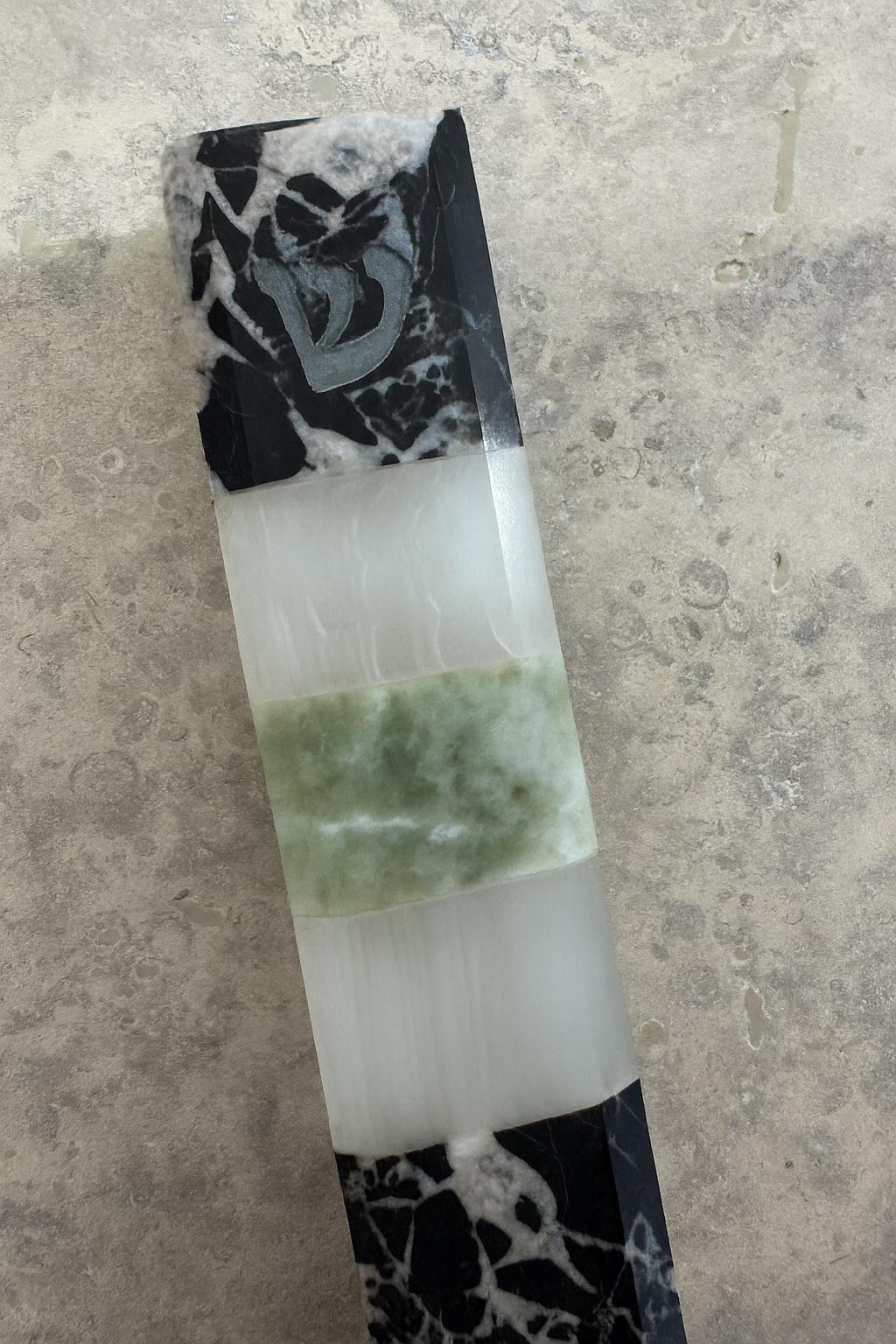 Esta Mezuzah escultórica de Studio Gaïa reimagina un símbolo intemporal de protección a través del lenguaje de la piedra, la luz y el equilibrio.

Elaborada con mármol Grand Antique, ónice blanco y ónice verde, la pieza revela un diálogo entre