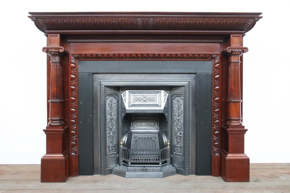 A large and magnificent carved pillared Victorian mahogany antique fireplace surround. The shelf, under carved with deep gadrooning, rests above a plain frieze topped with dentil moulding. Each of the panelled capitals sit above tapering and fluted