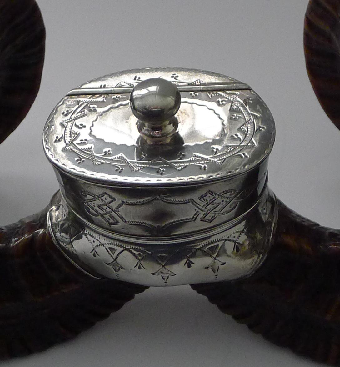 A very grand table-top snuff box which would have stood in a very grand home, made from a large Ram's horn with silver plated fittings including two bun feet.

The central snuff box is beautifully engraved. An impressive piece and an impressive