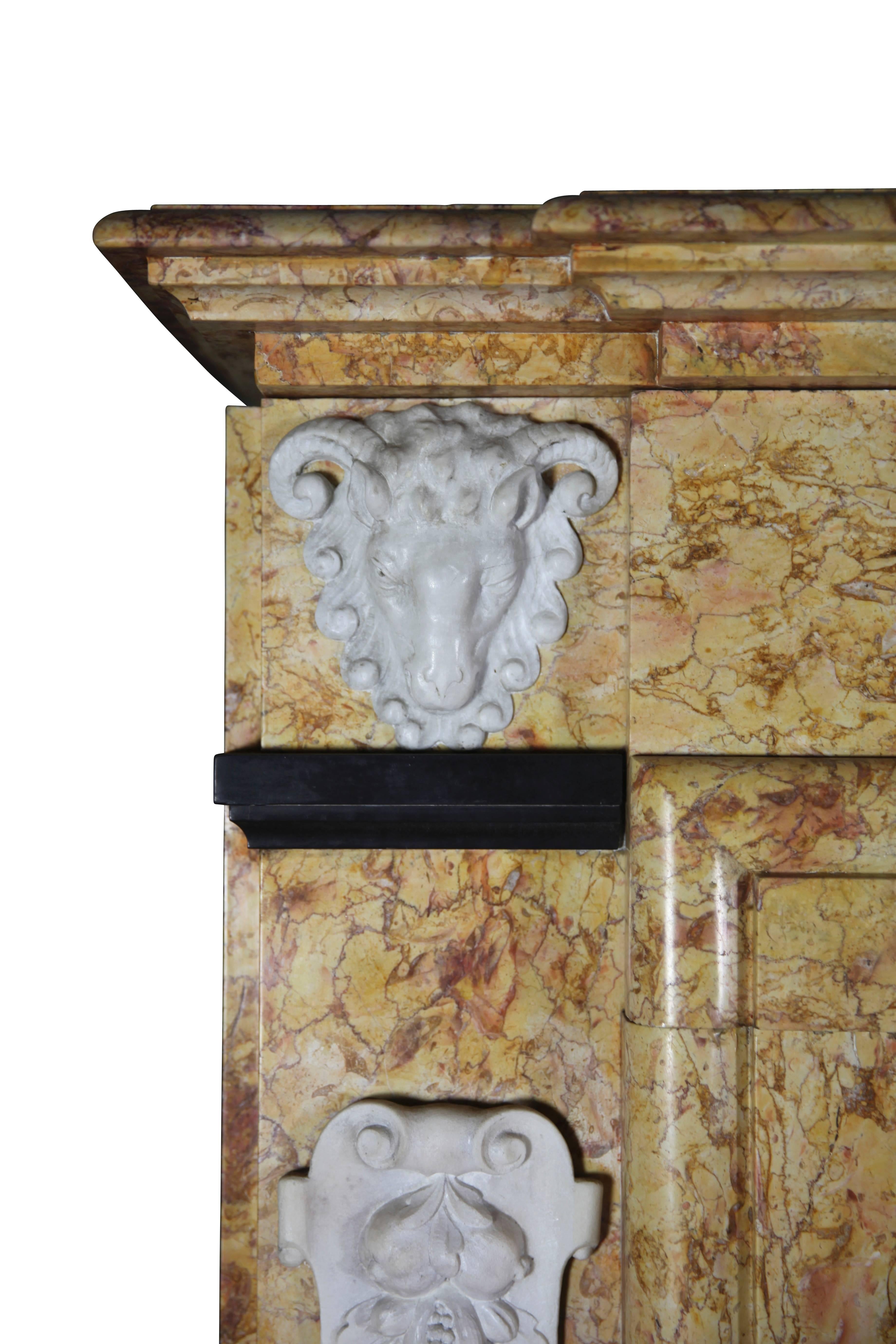 This antique fireplace mantel (fireplace) is one of a kind. It has been executed in Brocatelle d'Espagne marble with Black Belgian Mazy marble details. The angel head and the capricorn head are the proof of the highly skilled craftsmanship of this
