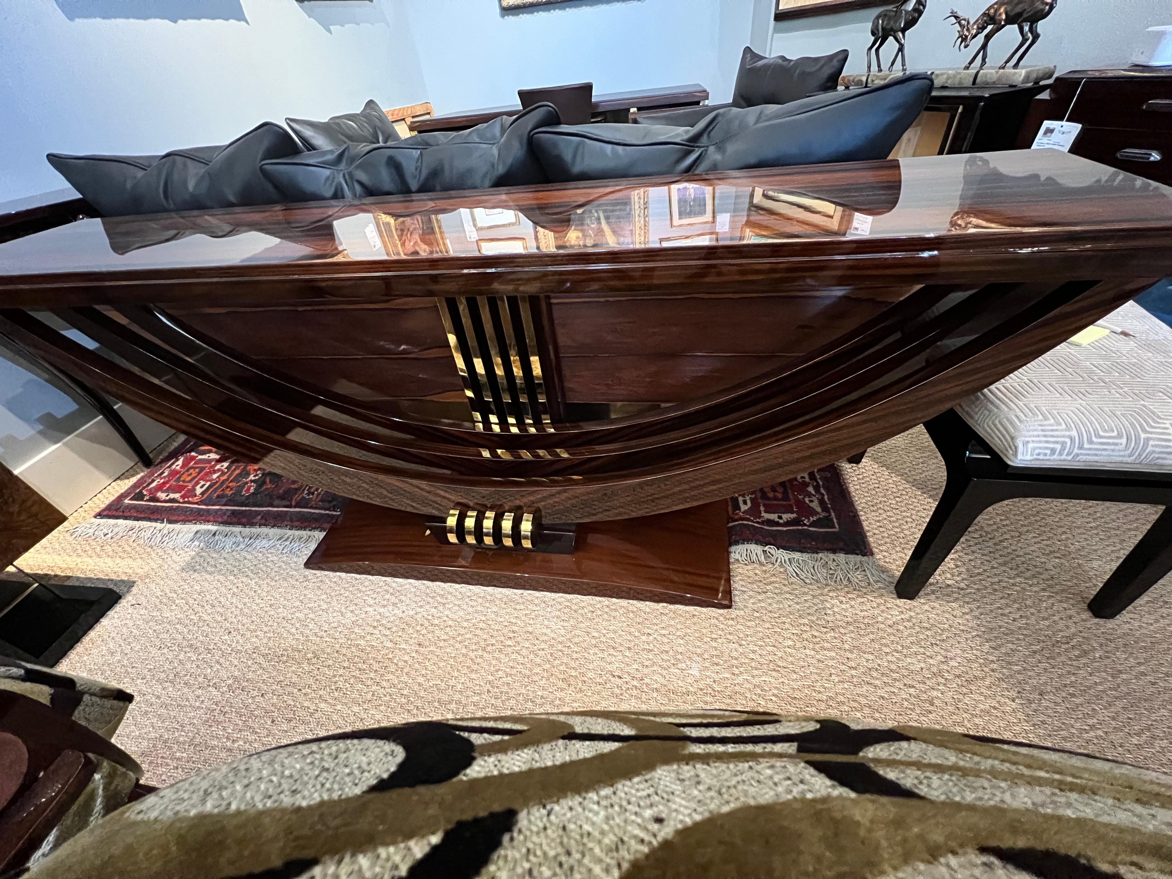 Console is made out of Macassar wood. Table top is elevated by 3 curved wooden legs. They are stabilized with trapezoid base. On the back of the console there is wooden panel with 5 brass decorative lines. 
Condition is excellent. Restored 

France,