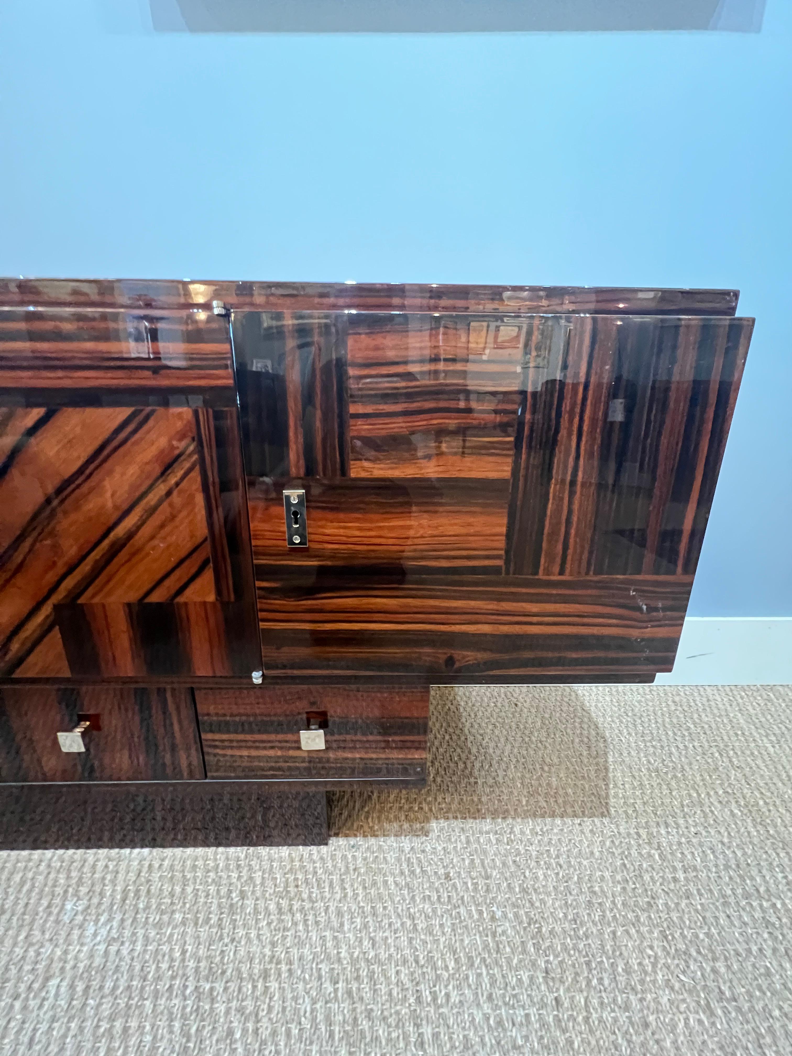 La credenza presenta un'eccezionale intarsio in legno che viene mostrato con orgoglio sulla parte anteriore della credenza. La credenza è composta da tre forme rettangolari poste una sopra l'altra. La parte superiore ha 4 cassetti grandi e la parte