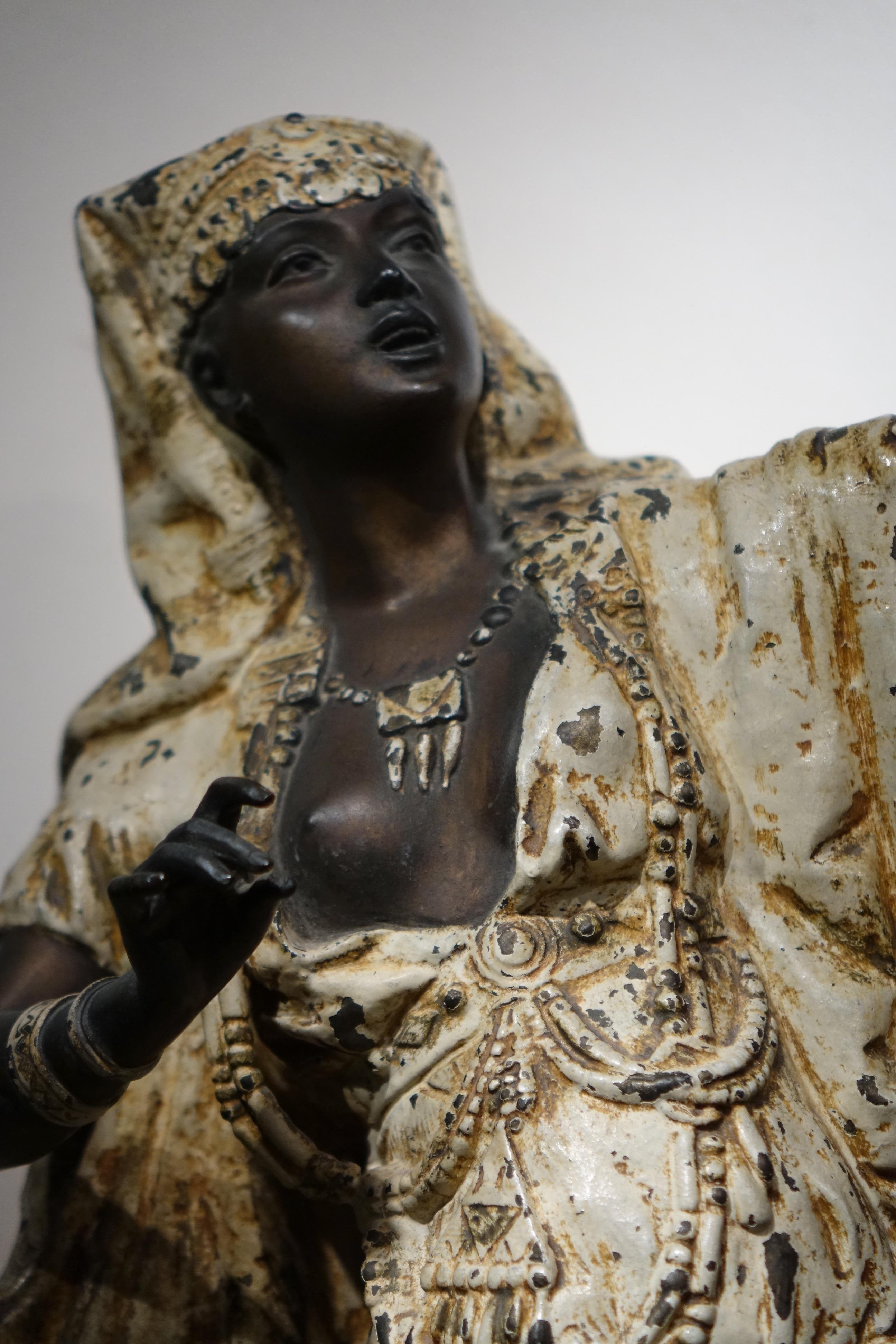 Large Babbit metal statue a woman dressed as an Egyptian, a bare breast, showing part of a deck of cards, the rest of which is on the sideboard at her feet.
 We have the impression here of a fortune teller in an Egyptian costume, somewhere in the
