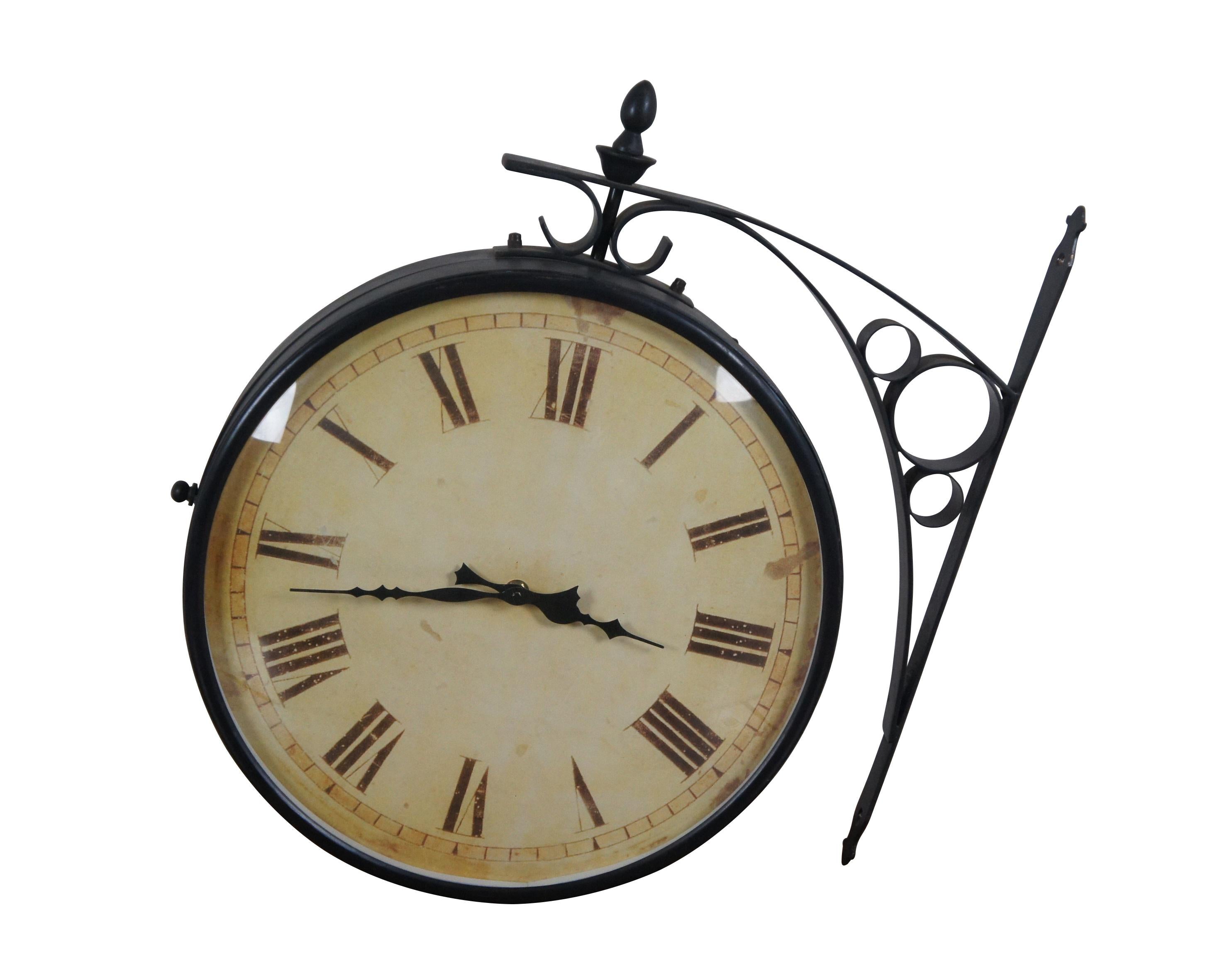 Late 20th century double sided railway clock styled after the famous clock at Victoria Station, London. Wrought metal wall mounted support and case in a dark bronze finish. 14 inch diameter printed face with faux distressing and Roman numerals.