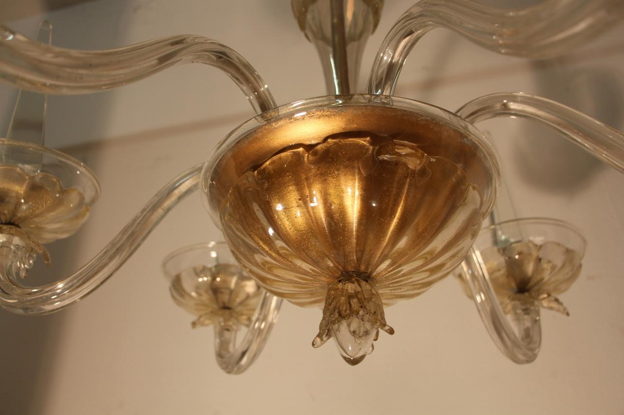 Grand lustre en verre de Murano transparent avec des inclusions de paillettes d'or, avec six appliques terminées par des coupes surmontées d'un obélisque. Bibliographie : Modèle similaire répertorié à la page 264 dans Arbus par Y. Brunhammer, Éd.