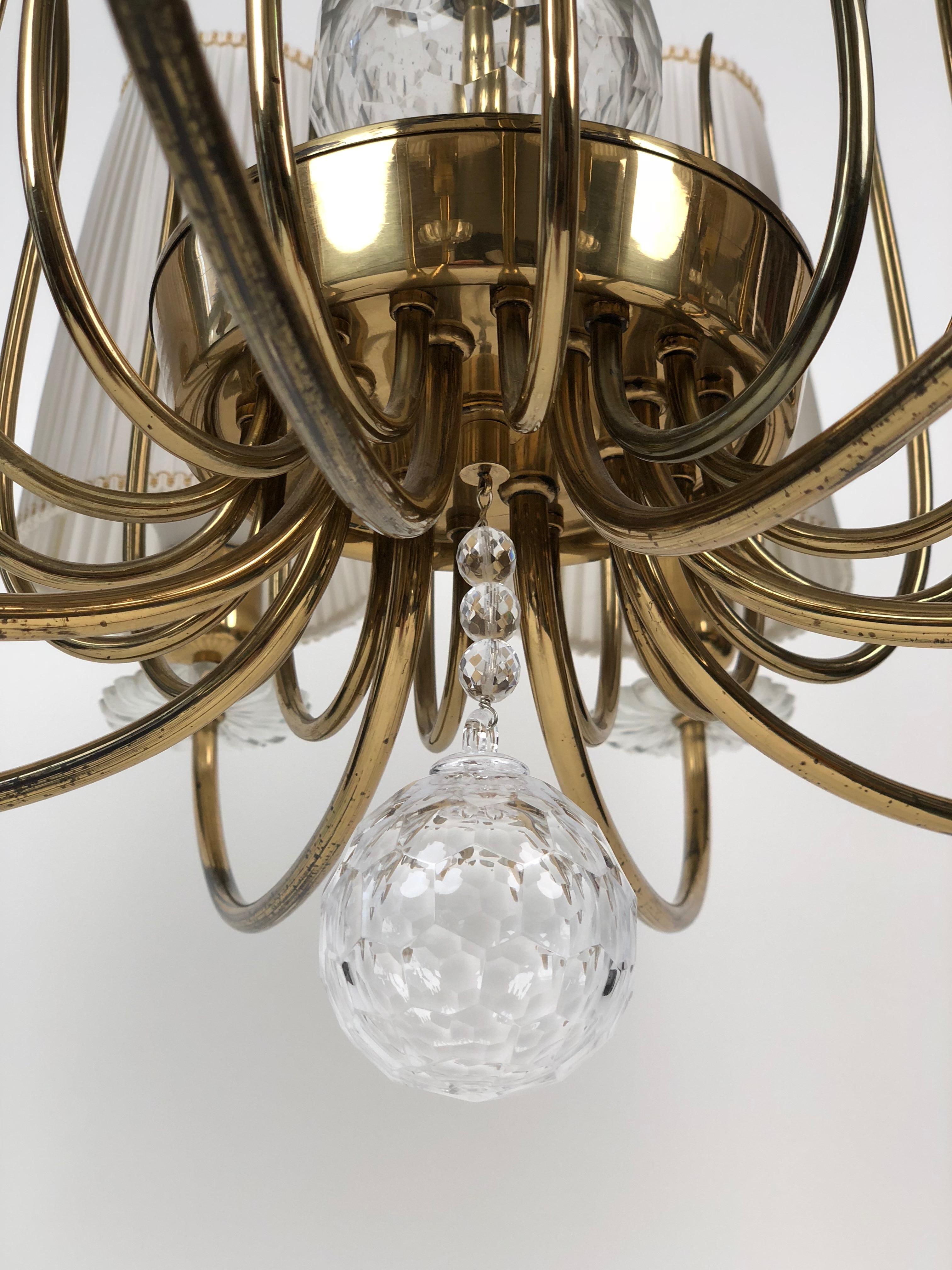 Elegant chandelier from Austrian producer J. L. Lobmeyr with 8 arms, crystal elements and original shades in white silk.
The pendant lamp has the possibility to use only the half of the lights, through switch.
      