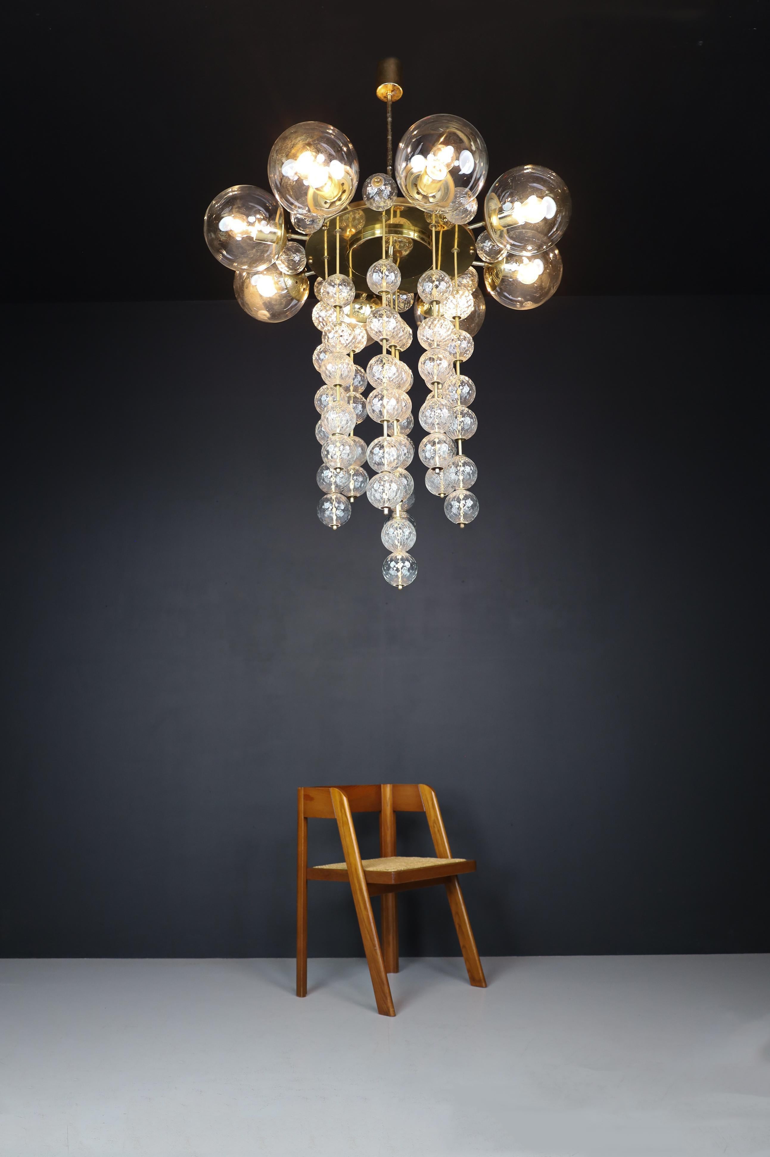 Grand Chandelier with brass fixture and hand-blowed glass globes, Czechia 1950s

This large chandelier with a brass fixture and hand-blown clear glass globes was designed and produced in Czechia during the 1960s. It features eight large clear glass