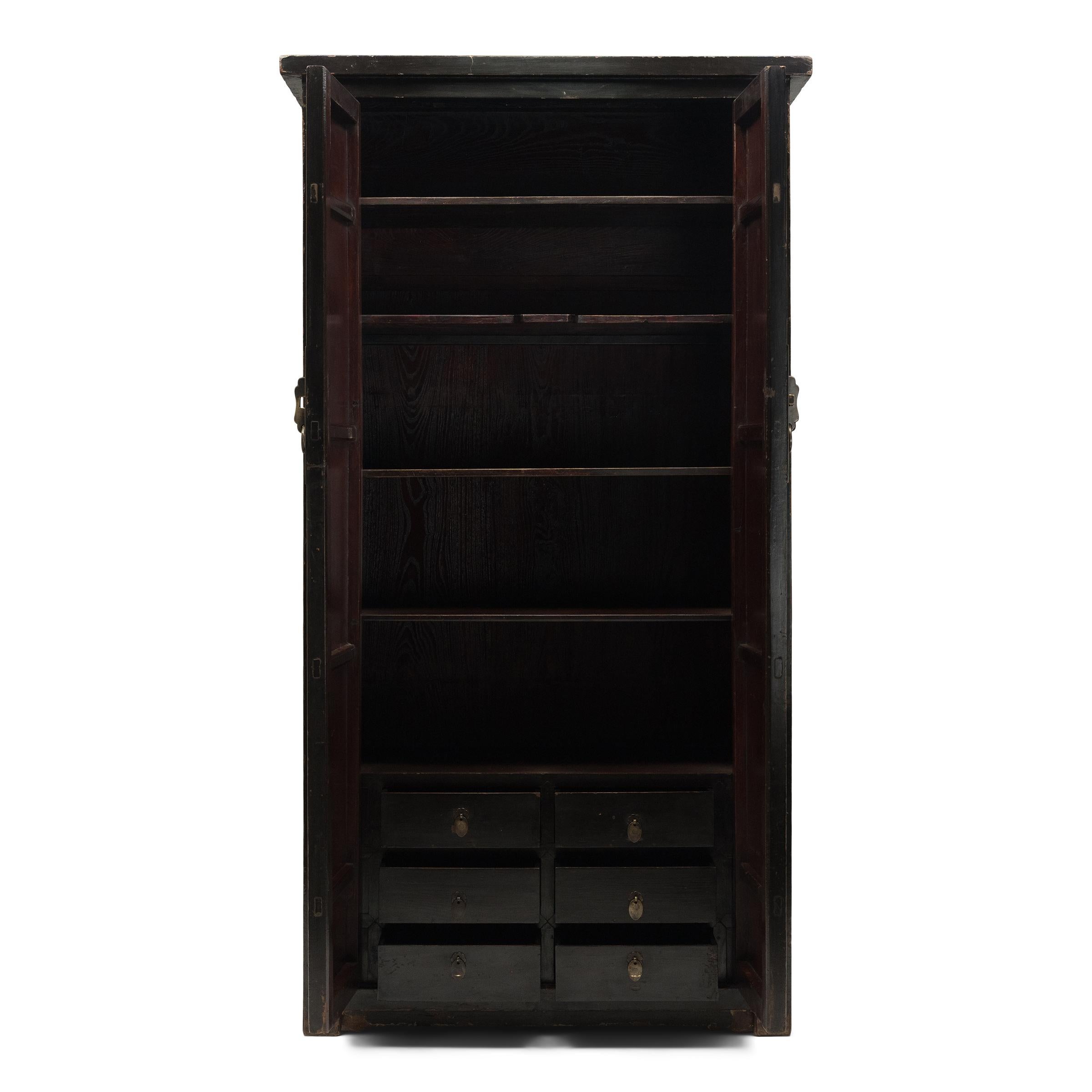 Ce grand meuble en laque noire incarne la beauté austère du mobilier chinois classique. Datée du milieu du XVIIIe siècle, cette grande armoire est fabriquée en orme du Nord (yumu) avec une menuiserie traditionnelle et présente des côtés droits, un