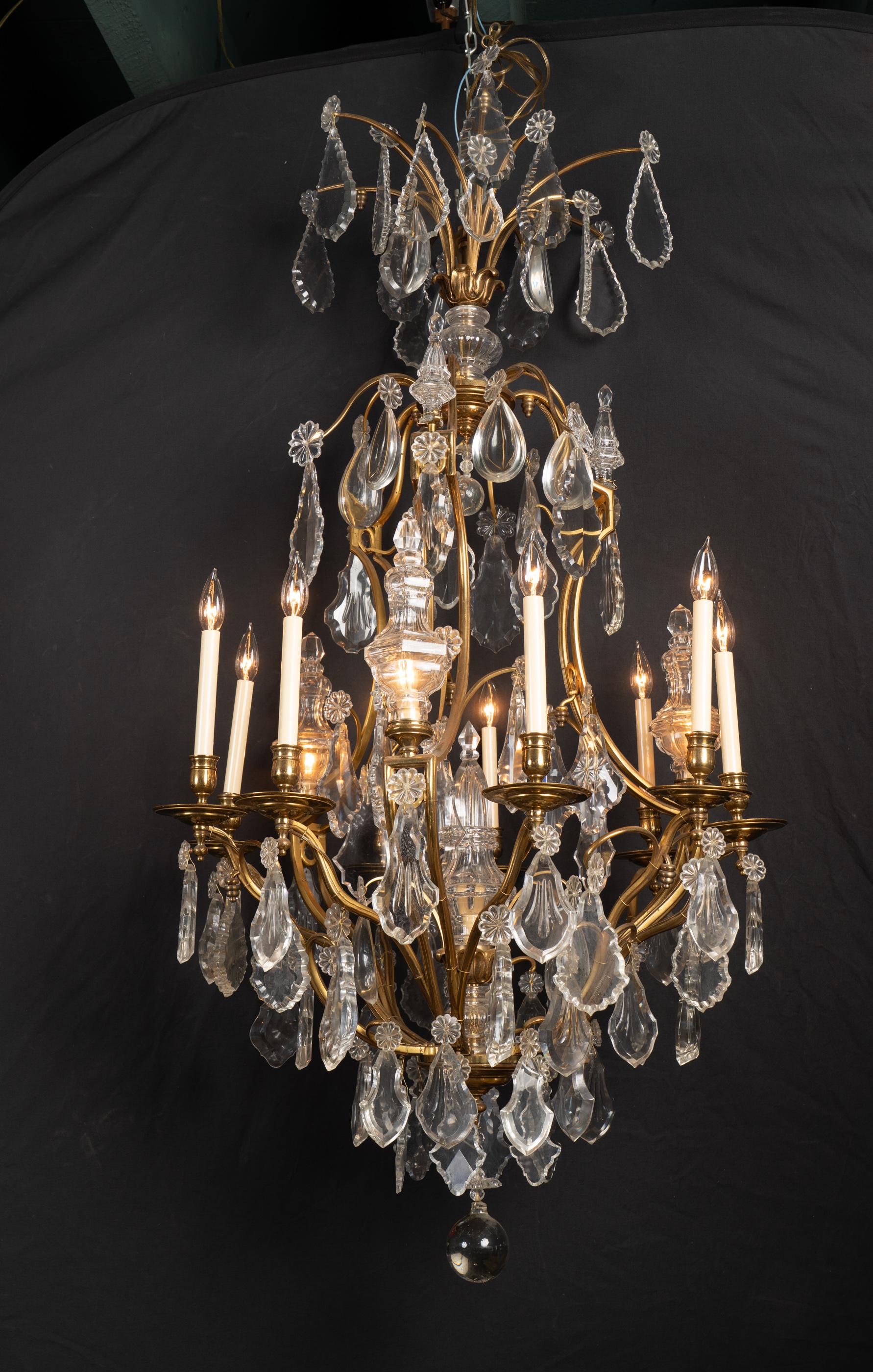 This beautifully grand Louis XV chandelier features bronze d'ore and crystal and dates back to the 19th century. The piece sports the Louis XV style with grace, and hosts a delightful selection of large crystal plaquettes and stately crystal