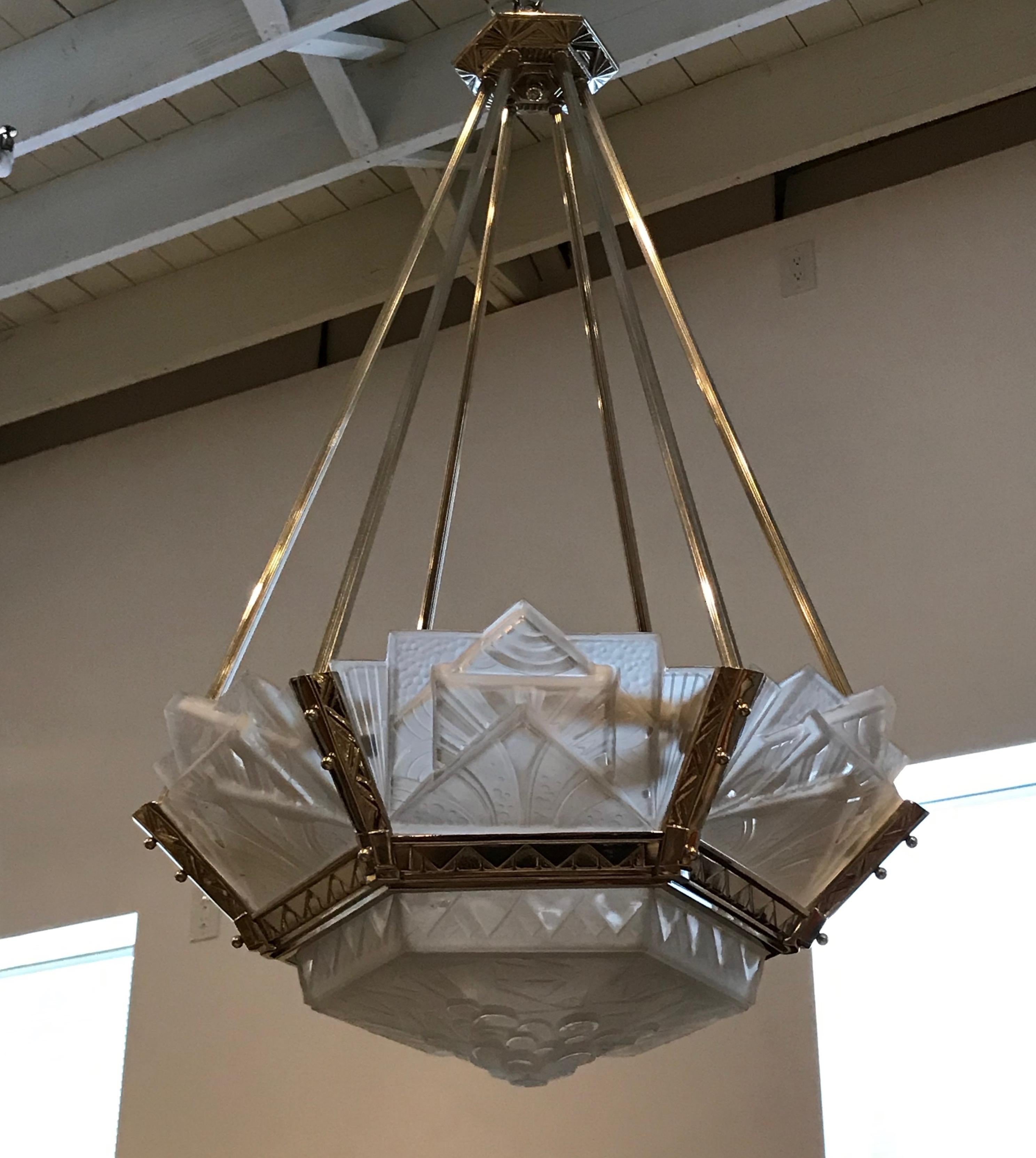 French Art Deco geometric chandelier signed by Muller Frères Luneville. Having clear frosted glass with over flowing geometric motif details. Supported by matching layered multi-tiered geometric polished nickel design frame. Has been rewired for