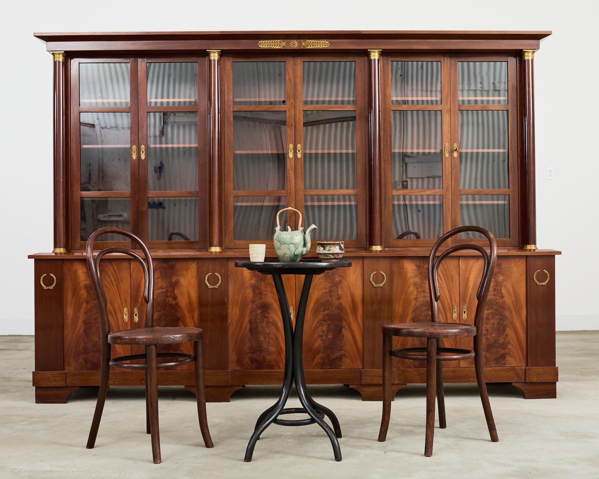 Opulent French mahogany bibliotheque style bookcase cabinet crafted in the Napoleonic French empire taste. Constructed on a grand scale the cabinet features three pairs of storage doors on the bottom of the case with radiant mahogany veneered