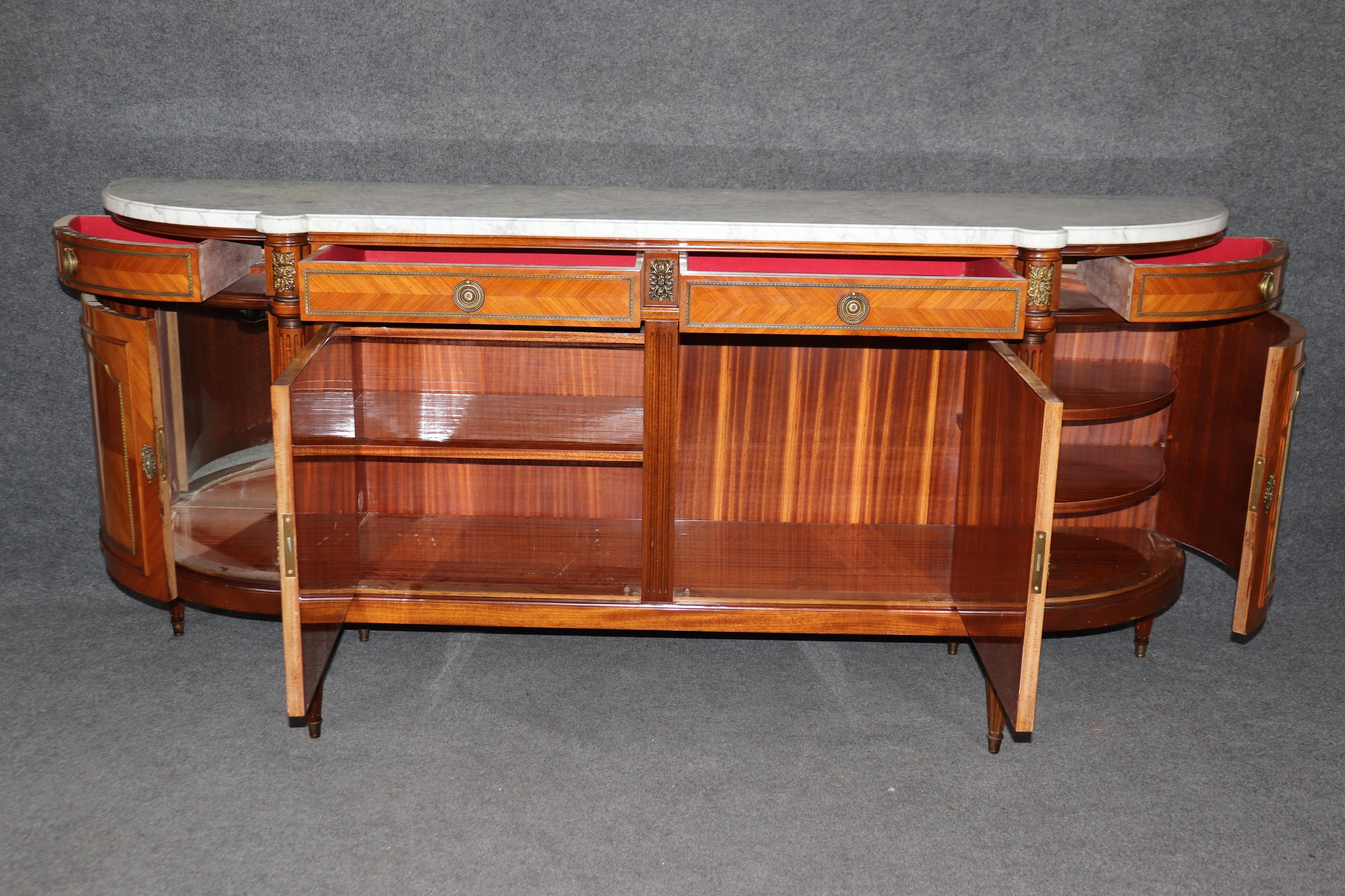 This is a grand and very shallow depth sideboard that was made in France during the 1950s era in the Maison Jansen style. The piece is made of kingwood and features gorgeous parquetry panels of kingwood and brass trim and bronze ormolu. The white