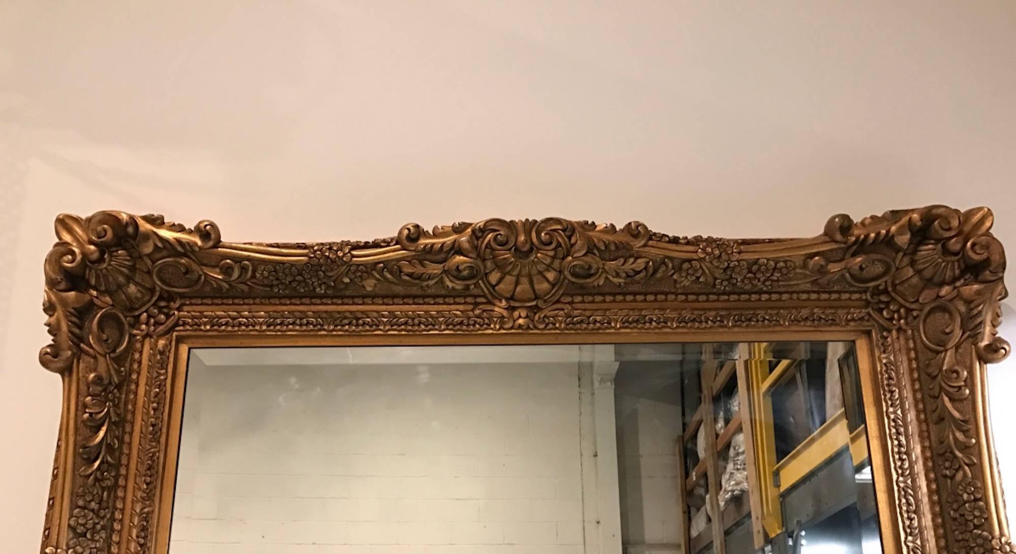 Großer Spiegel aus vergoldetem Holz mit handgeschnitzten, verschnörkelten Details. Mit abgeschrägtem Spiegel.