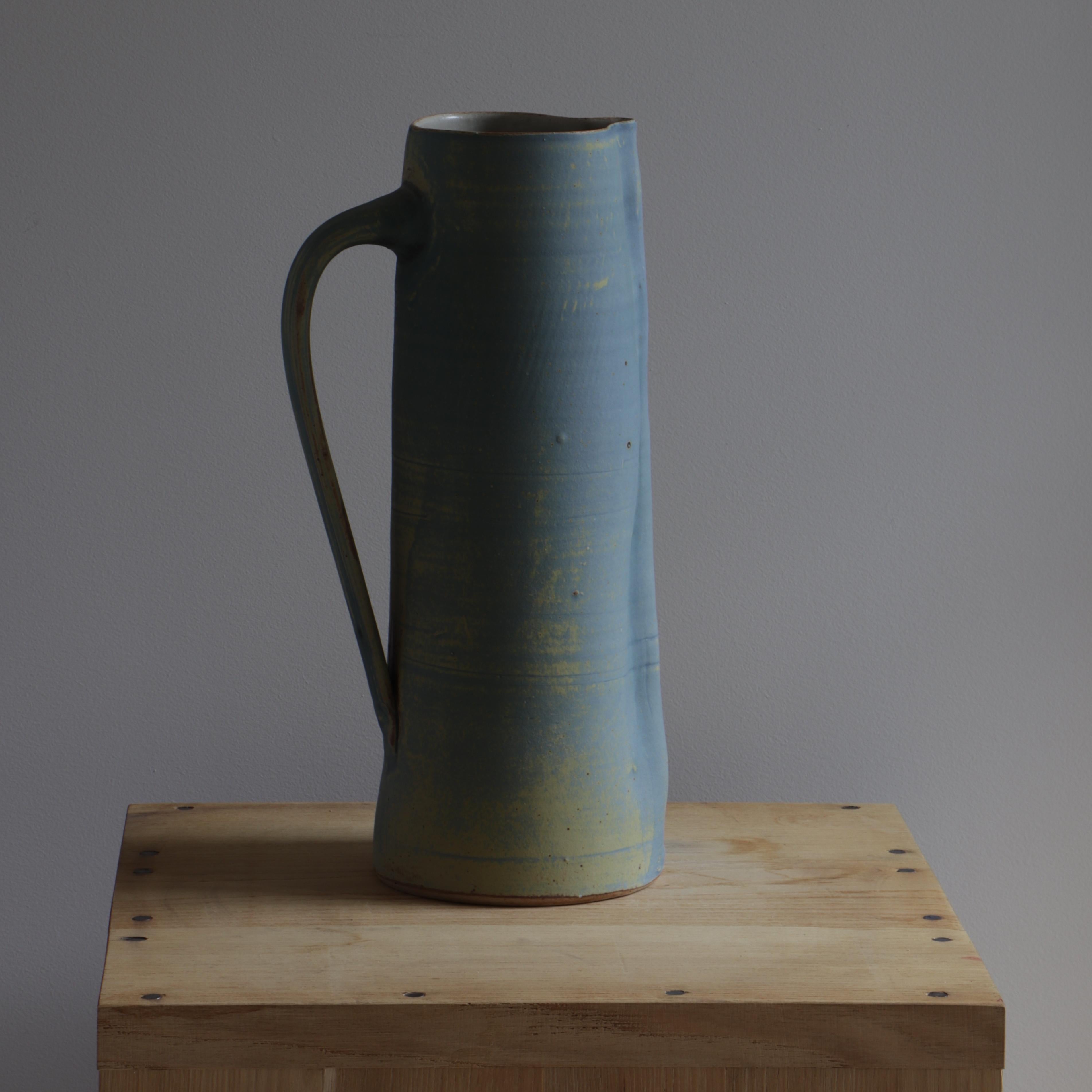 This ceramic jug was created by Ingrid Van Munster. Her works are made of porcelain sandstone. The colourisation phase consists in covering her pieces with enamel, after a first firing at 1000°C. She manufactures her own matt and satin enamels in a