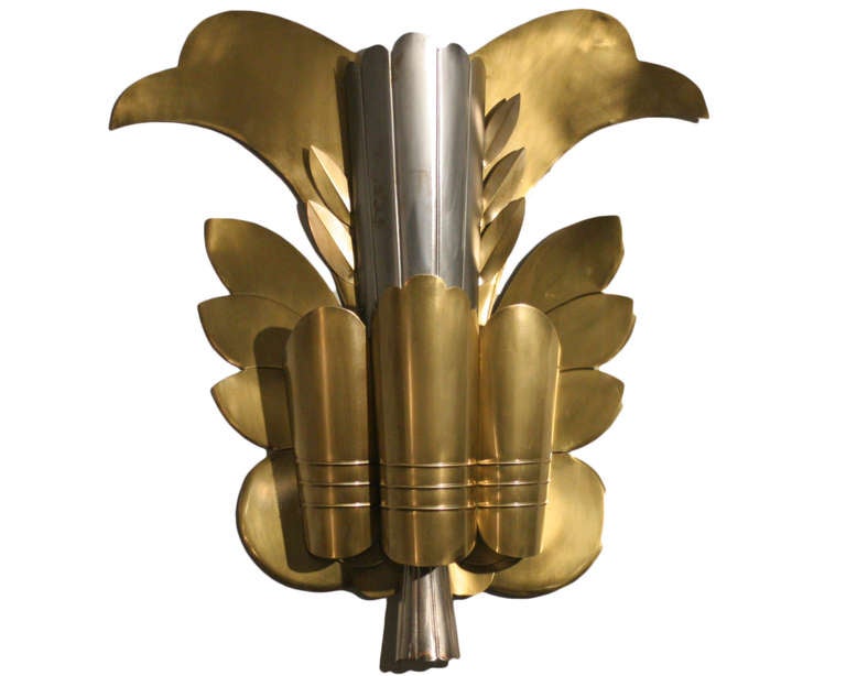 This stunning, large-scale sconce custom made for a Hollywood theater during the early 1930s. It is composed of interlacing brass, polished aluminum and leaf shaped accent lights encasing from behind the polished center.

   