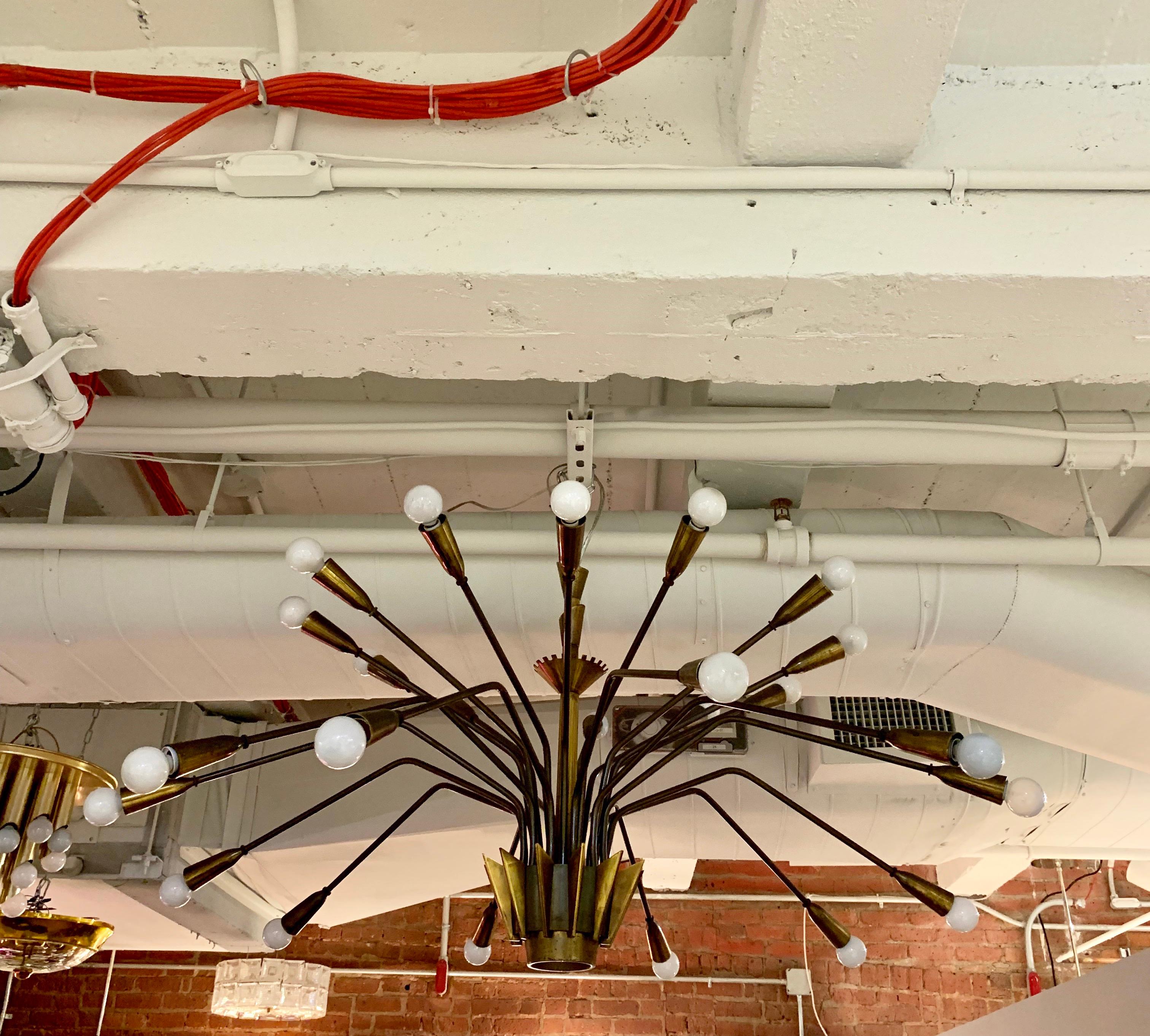 A large 24-arm aged brass chandelier with a single center downward light. The center has decorative mod century fins. Newly rewired. A rare design.