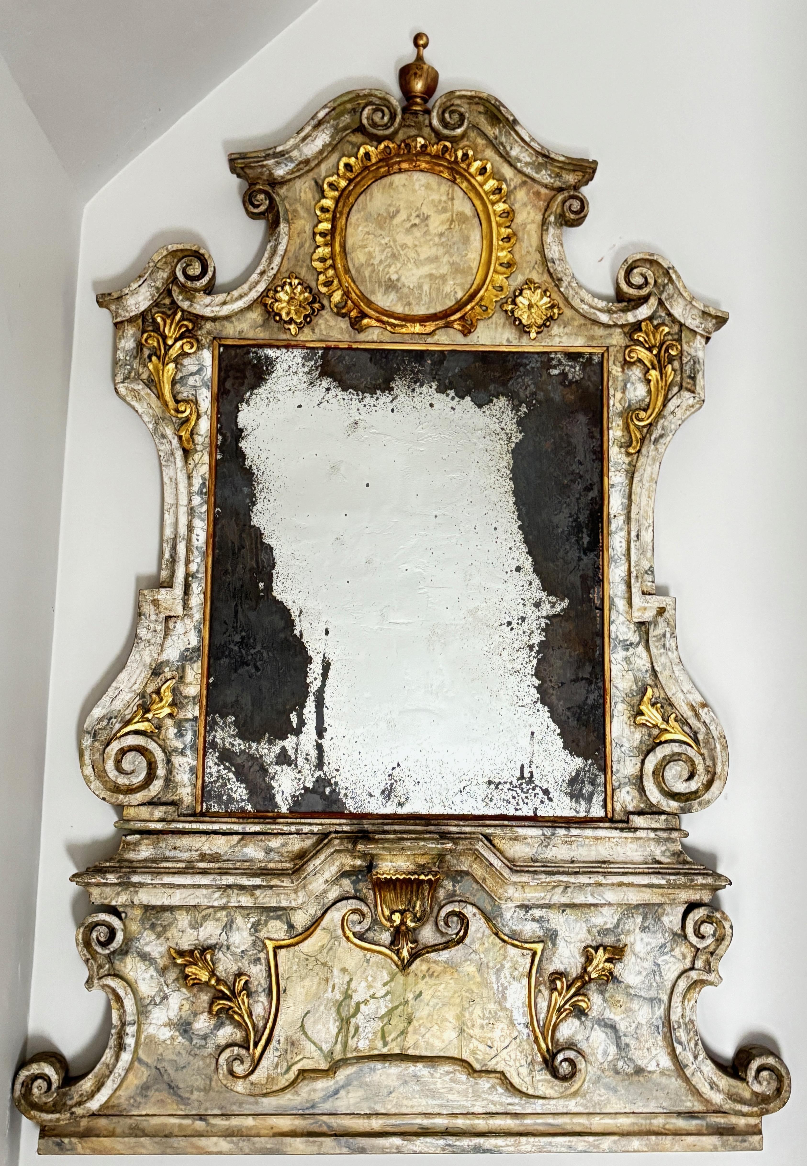 Grand miroir de style baroque en bois sculpté, gesso et doré, avec finition en faux marbre d'origine. La plaque de miroir est ancienne mais n'est peut-être pas d'origine.
Il s'agit d'un miroir qui aurait été accroché dans un impressionnant palais ou