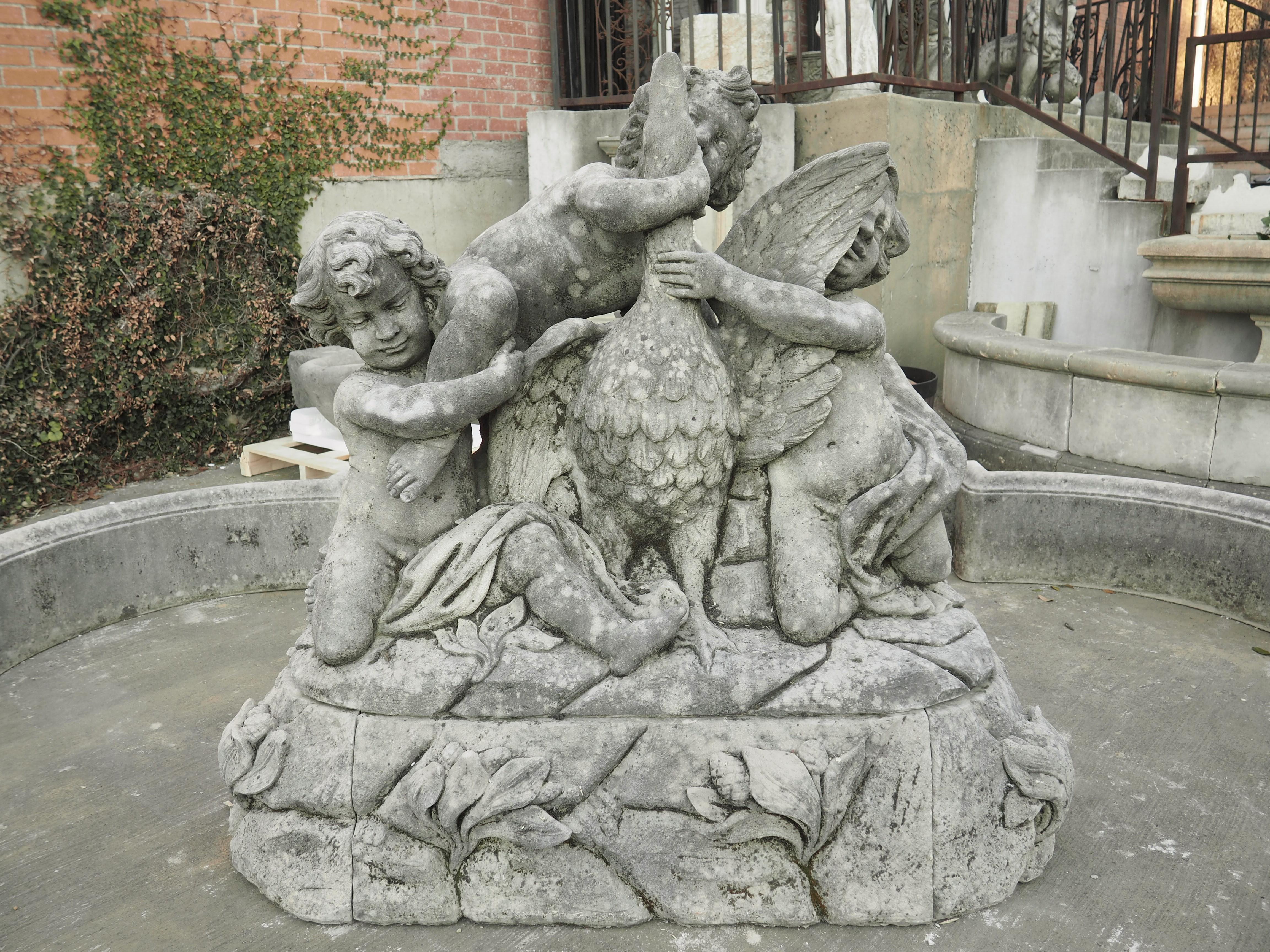 This grand Italian limestone center fountain features a large center element of three putti playing with a goose. These putti are portrayed as mischievous children, wrestling with the highly plumed bird on top of uneven terrain. Carved from one