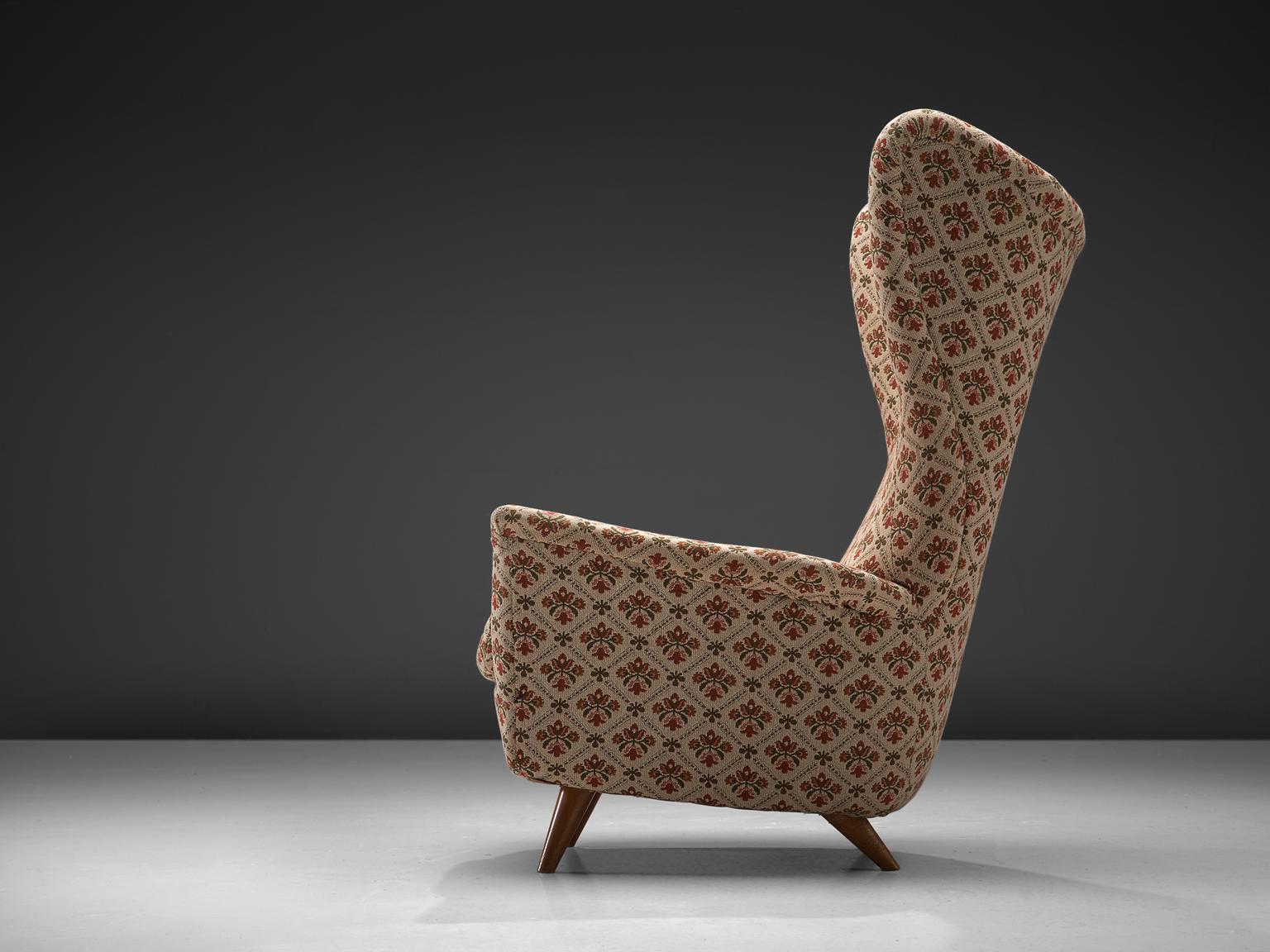 Large Italian wingback armchair in the style of Gio Ponti, decorative floral fabric, beech wood legs, Italy, 1950s.

This Classic Italian wingback chair has all the traits of Midcentury Italian design. The unusually high back, the gracious wings,