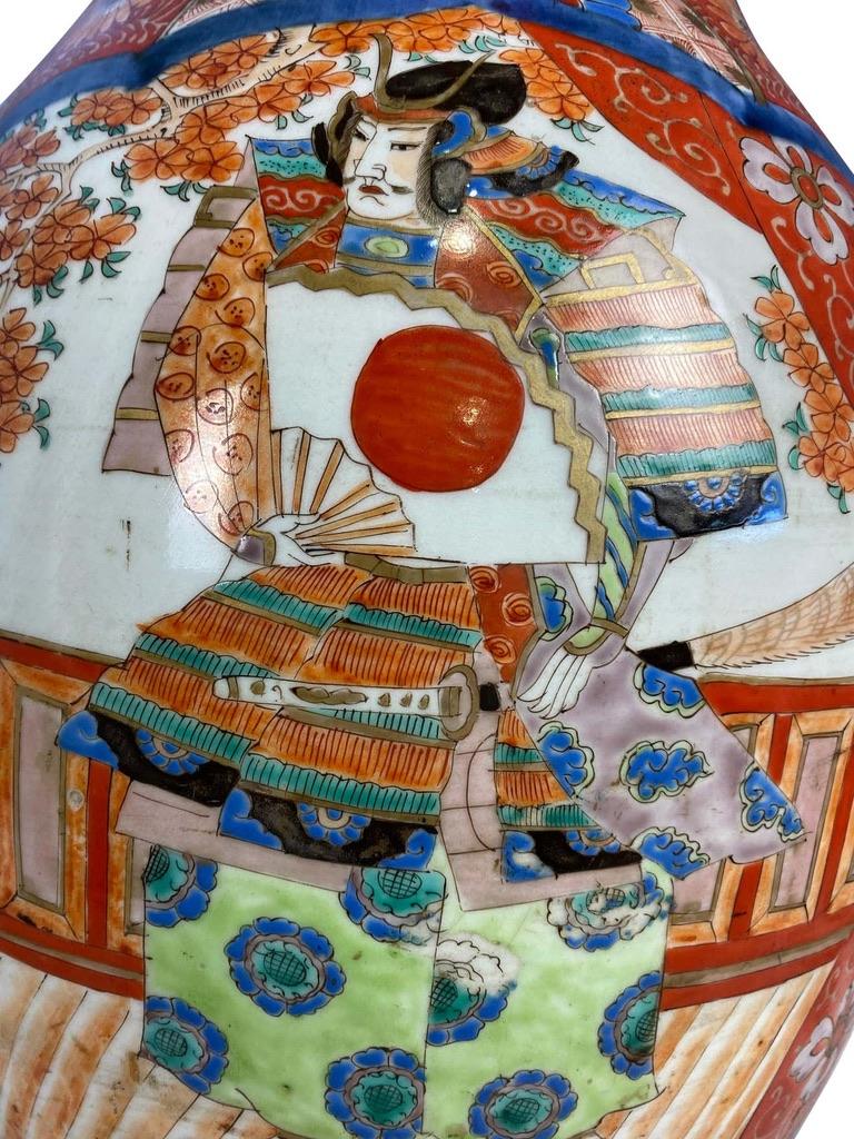 A grand Japanese porcelain Imari vase hand painted with classical scenes. Likely to have originated from Arita in Hizen Province, Japan. The body shape is elegantly designed to have a narrow middle and incredibly wide top.