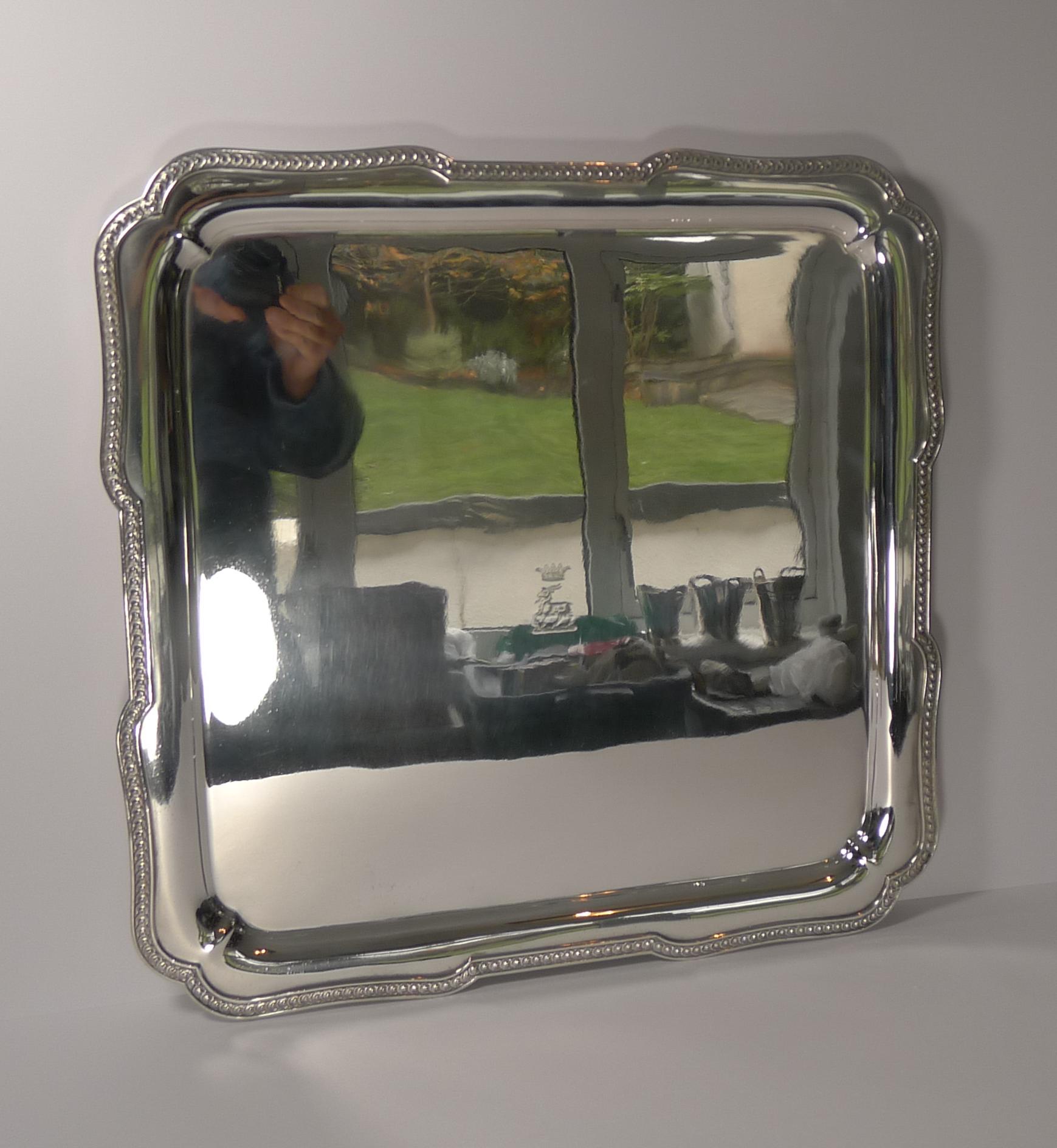 A magnificent square cocktail / drinks tray with a shaped border with a raised decoration.

The tray stands on four original bracket feet. The underside is fully marked by the creme de la creme of silver plate manufacturers, Elkington & Co. There