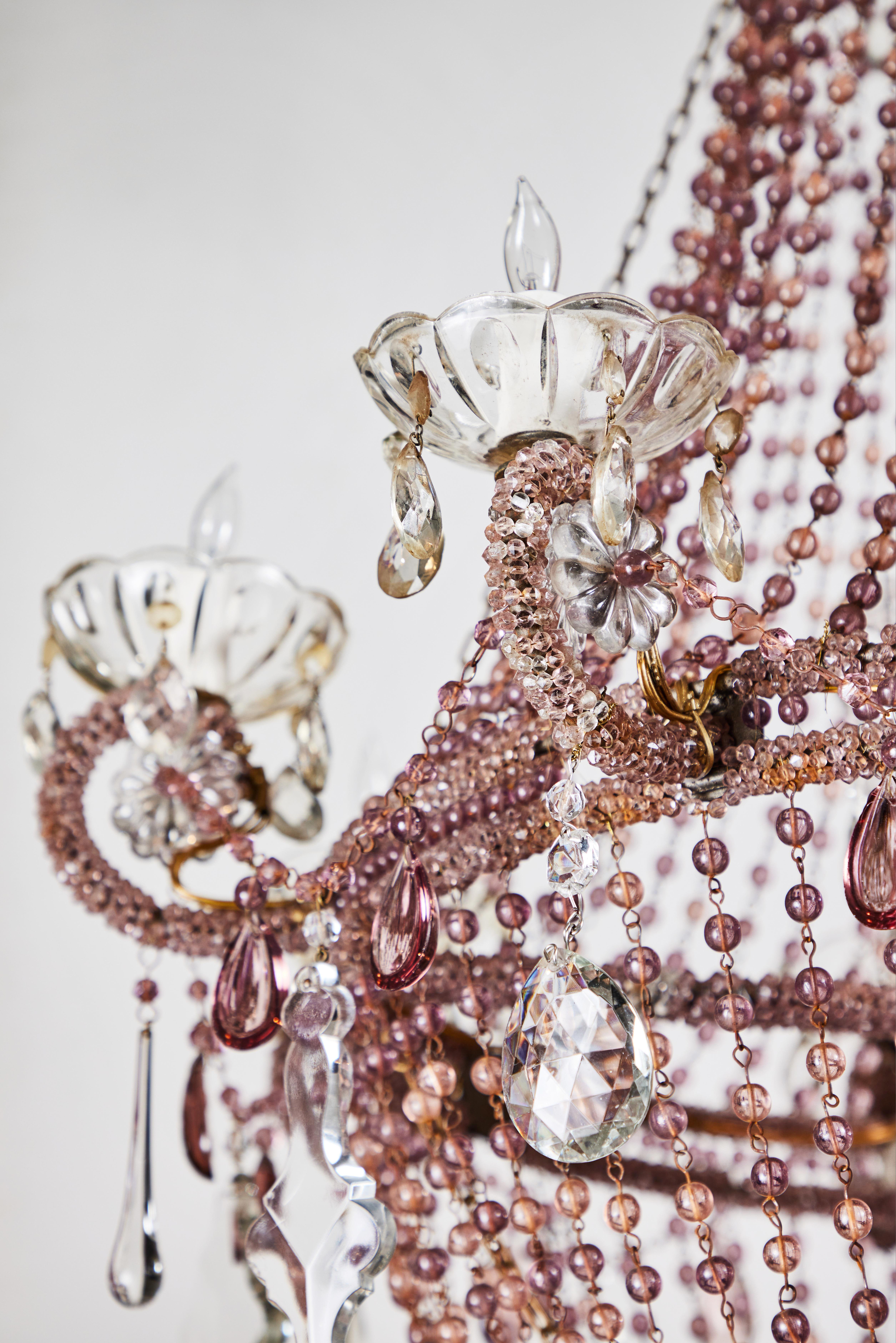 A large, lush, dramatic, French chandelier in lavender. Eight, curled, hand-beaded arms sit amidst a large basket of long swags of crystal terminating in a beautiful mix of tear drops and beveled edge embellishments. The central column encased in