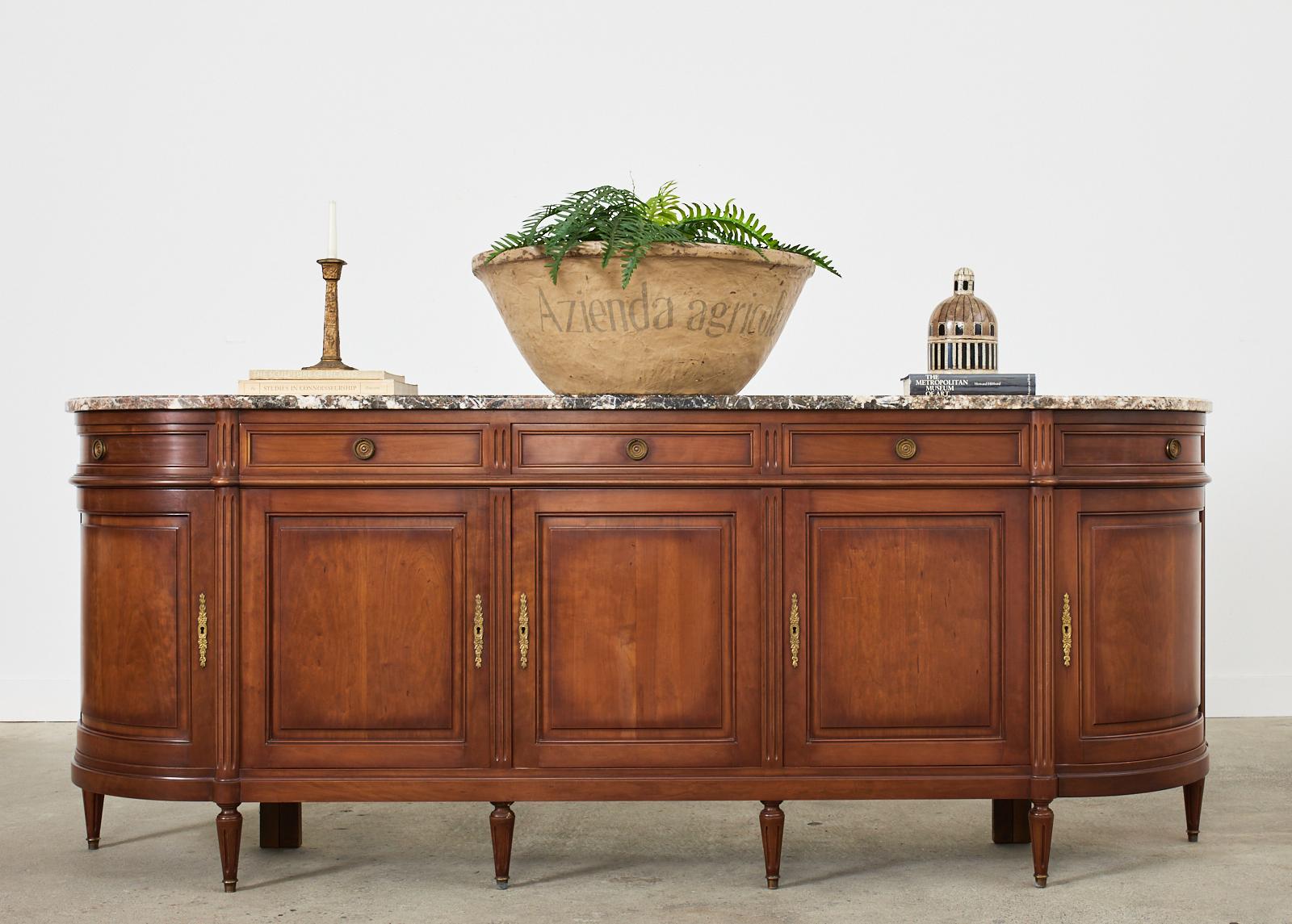 Grand French mahogany sideboard or buffet server featuring a thick variegated marble top. Beautifully crafted in the neoclassical Louis XVI taste. The mahogany case has classic French curved demilune ends with five drawers above five locking storage