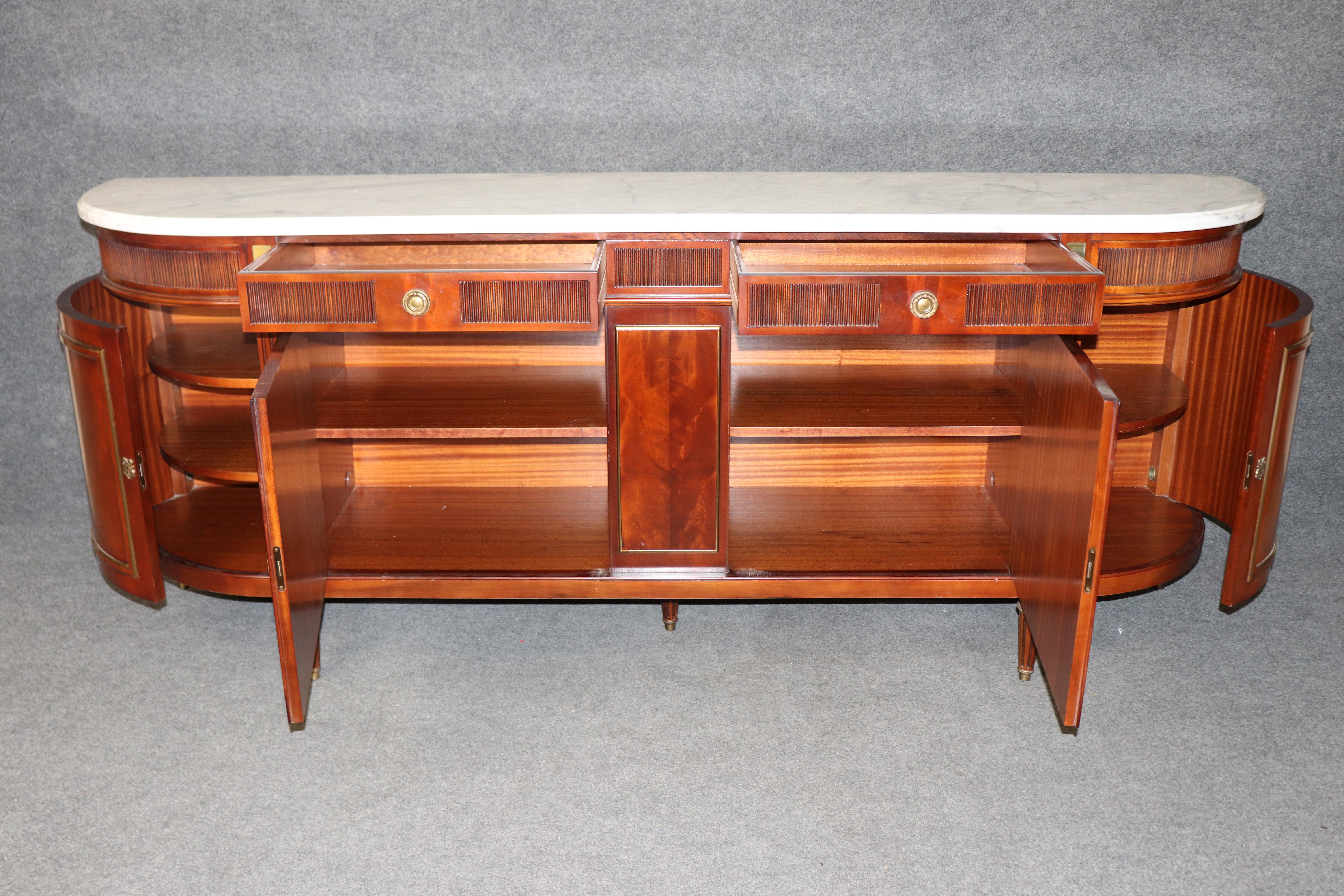 Fai una dichiarazione raffinata con questa credenza elegante e poco profonda in stile Maison Jansen francese degli anni '50, realizzata in mogano con una ricca venatura e impreziosita da finiture e dettagli in ottone. Questo pezzo sofisticato