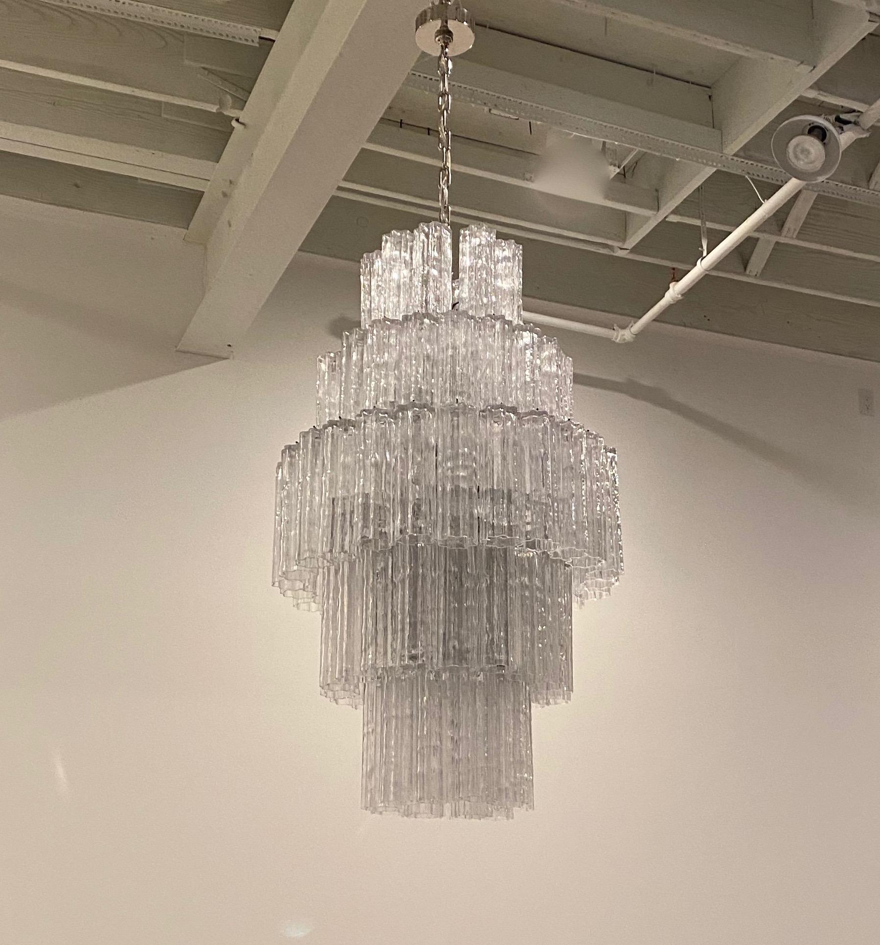 Mid-Century Modern tiered round chandelier. Consisting of tronchi cylindrical glass pieces. Each piece is hand blown and has a star or floral shape. The glass tronchi hangs from a nickel (silver) frame as pictured. Any amount of chain can be added