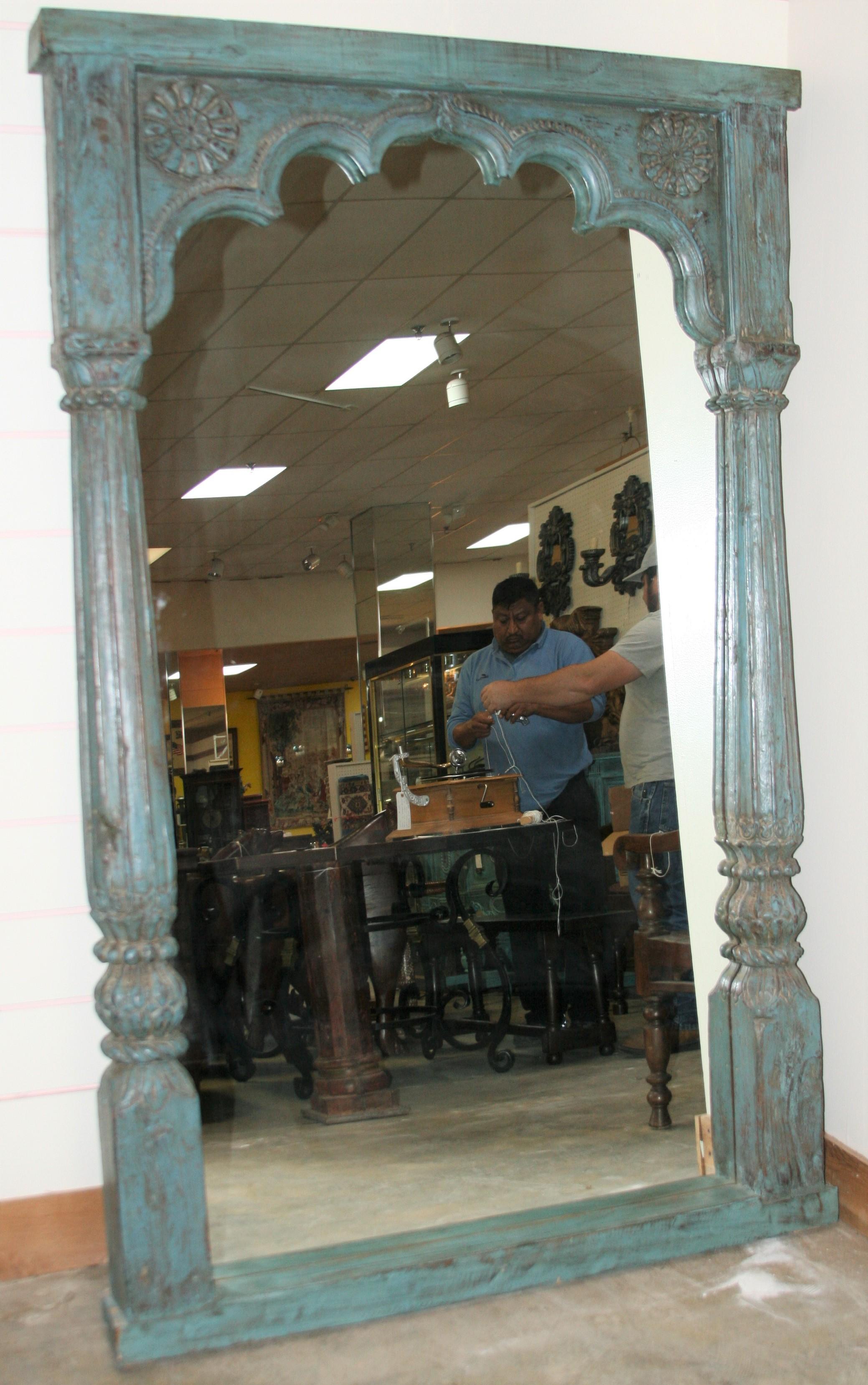 The solid teak wood frame for this large mirror comes from an old fort. In the long corridors of the forts these highly carved arches served as open windows. Exceptional hand carving. Retains original painting. Carved on both sides. Motif is